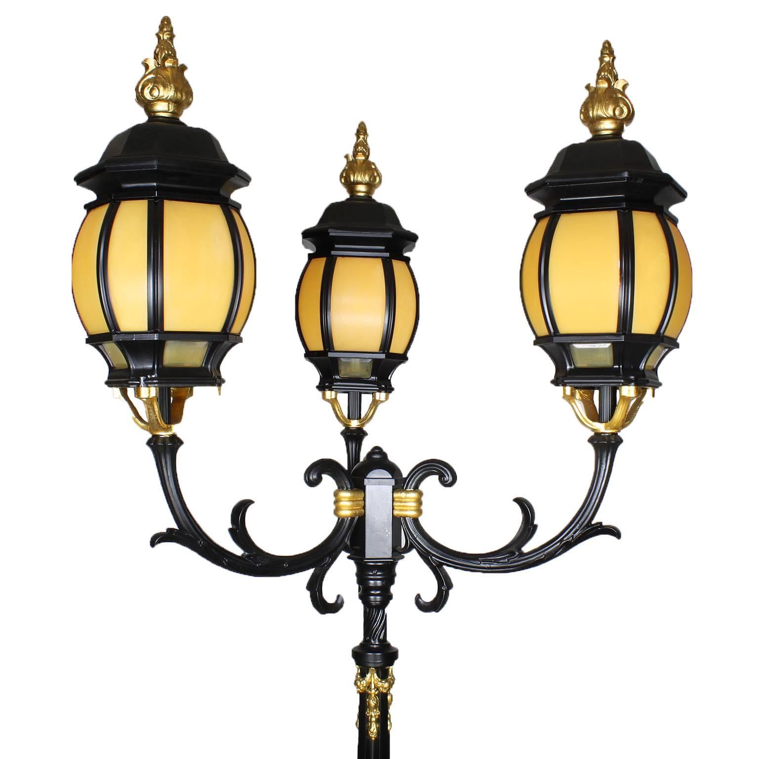 A Palatial Pair of French 19th/20th Century Neoclassical Revival Style Ebonized Cast-Iron and Parcel-Gilt Torcheres (torchières - Lamp Posts). The park-like torcheres surmounted with later three-form metal Lumières with bakelite mounted shades