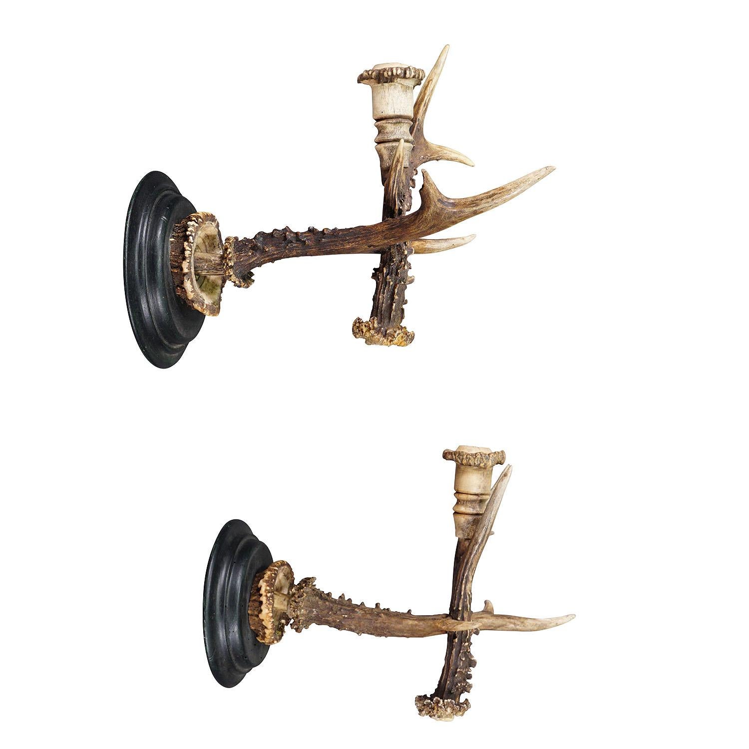 A Pair Great Black Forest Wall Sconces with Deer Horns, Germany ca. 1900

An antique pair of Black Forest sconces for candles. Each made of original deer horns which are mounted on a turned wooden base. Spouts made of turned deer horns too. Executed