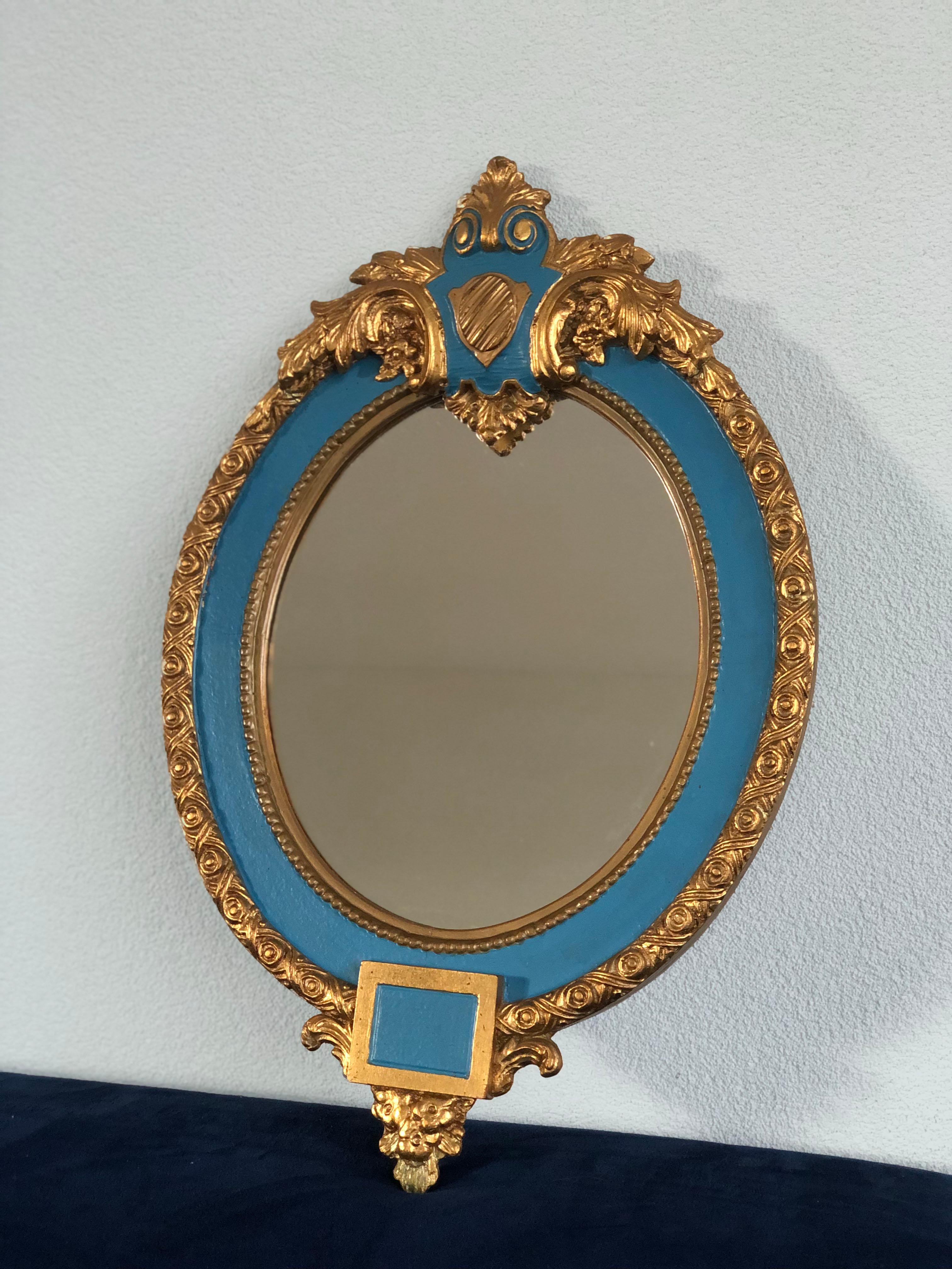 2 beautiful, very detailed oval giltwood crested mirrors from France. The frame of the carved wood is decorated with a floral and pearl rim. The plaster of the crest is finished with leaves and the whole mirror with a blue line of a later