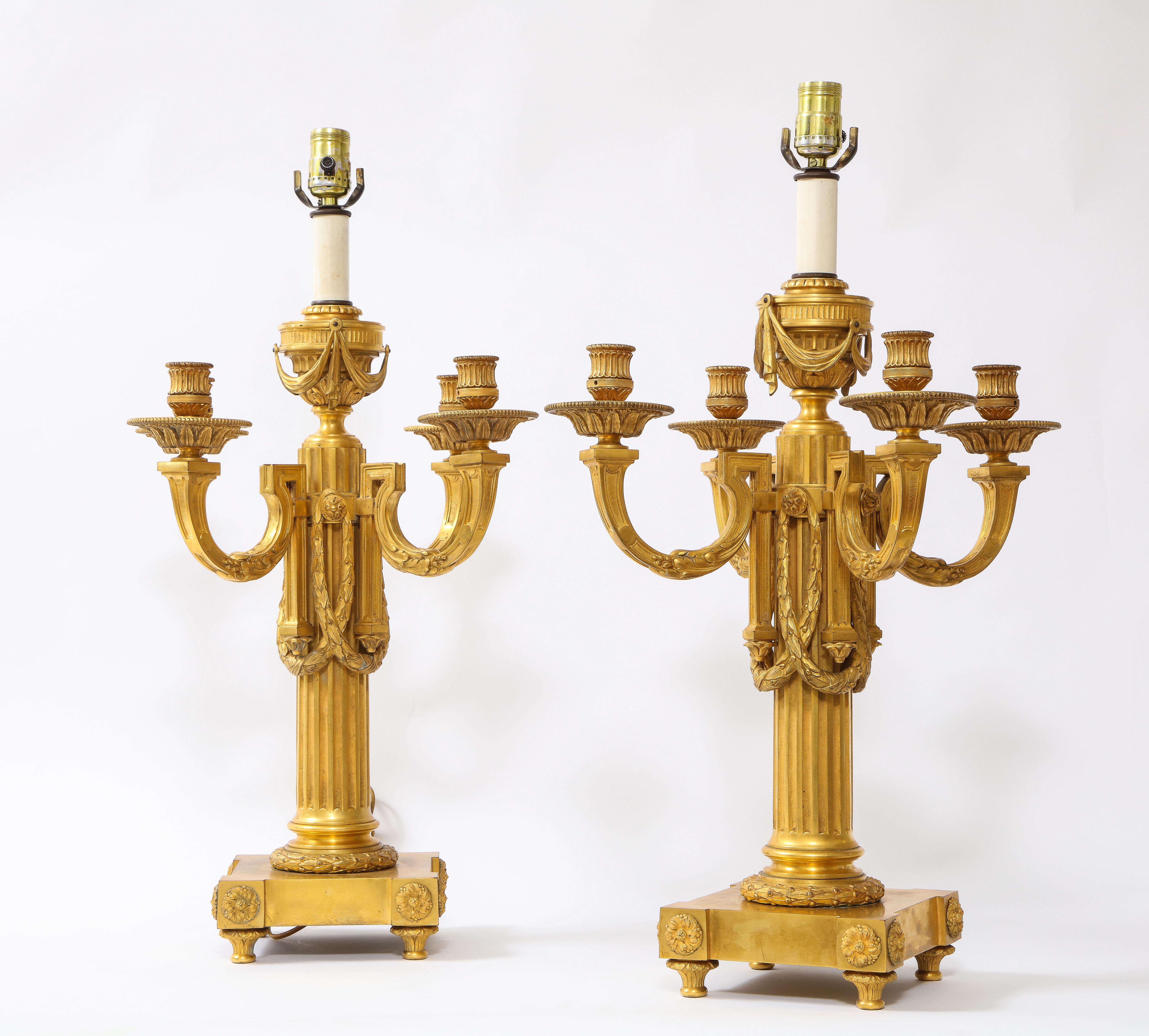 Pareja de candelabros franceses de cinco brazos de Ormolu del siglo XIX convertidos en lámparas.  Cada uno de ellos está excepcionalmente fundido, cincelado y cincelado a mano, con un alto cuerpo columnar que se extiende hasta cuatro brazos de