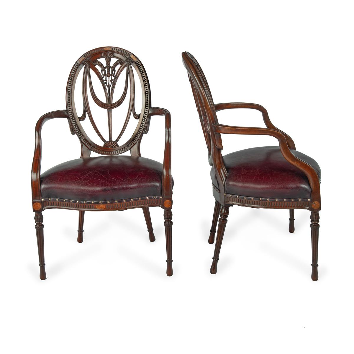 Ein Paar Mahagoni-Sessel im Hepplewhite-Stil, jeder mit einer ovalen Rückenlehne, die Prince of Wales-Federn mit Drapierungen und gebundenen Bändern umschließt, die geformten Arme und der serpentinenförmige Sitz auf gedrechselten, spitz zulaufenden