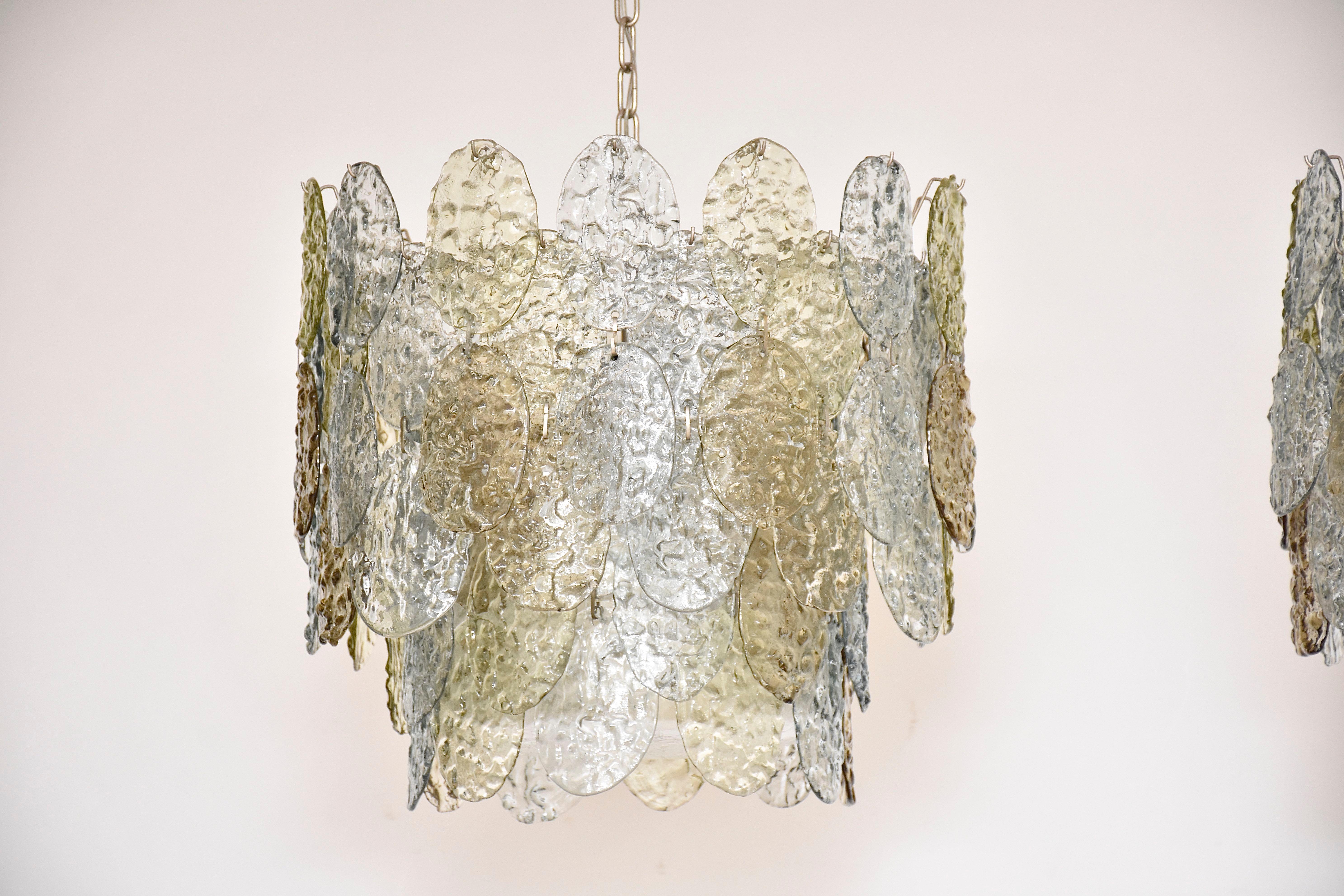 Una bellissima coppia di lampadari di Murano della metà del secolo scorso disegnati da Gino Vistosi.
Ognuno con 4 luci all'interno.
Decorato con pezzi di vetro di Murano trasparente, azzurro, champagne e marrone fumé lavorati a mano.
Questi pezzi di