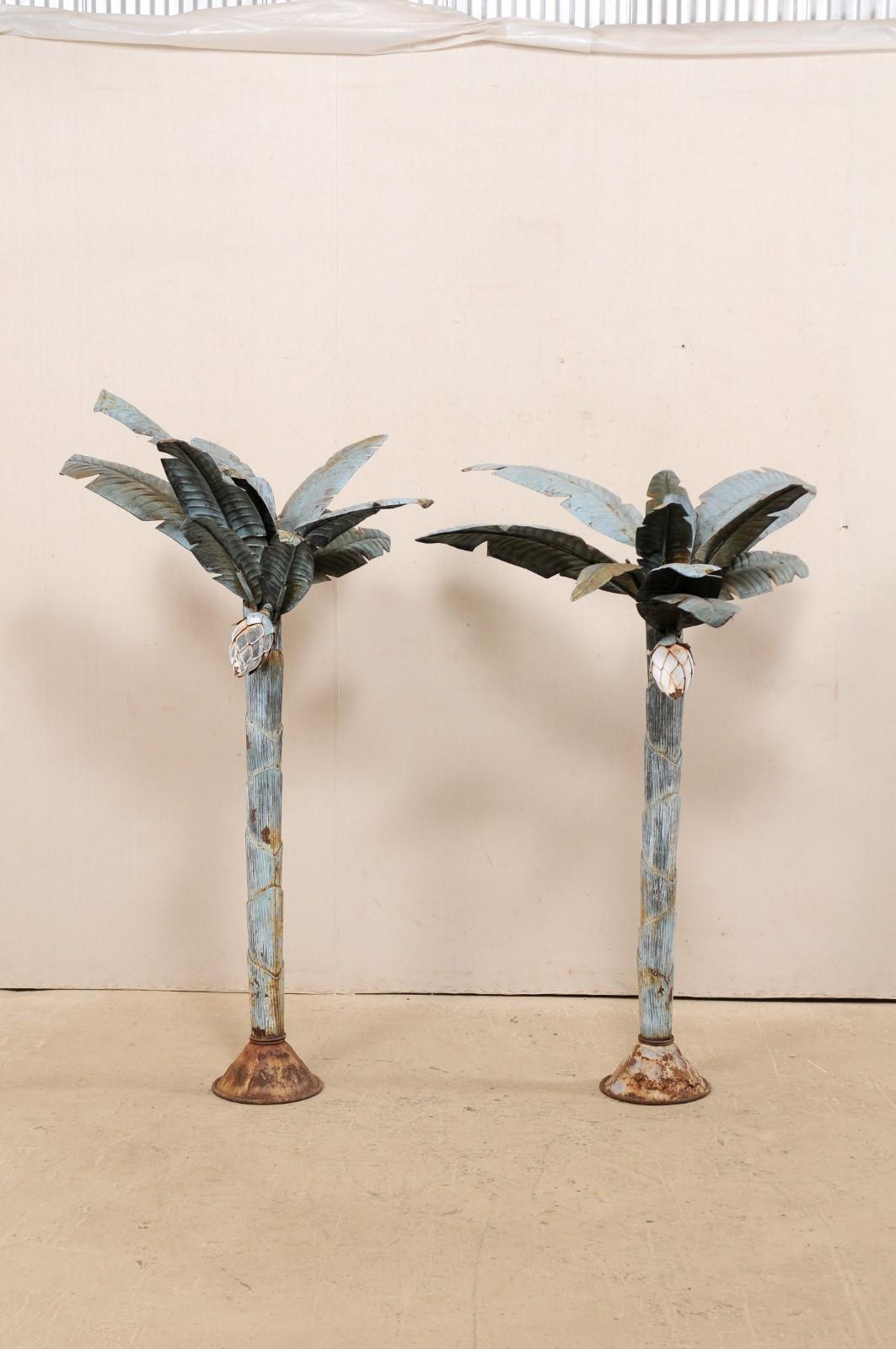 A pair of modern-designed and painted metal palm trees from the mid-20th century. This pair of vintage American whimsical metal sculptures, each standing approximately 5.5 feet in height, are replicas of a pair of palm trees, each having a single
