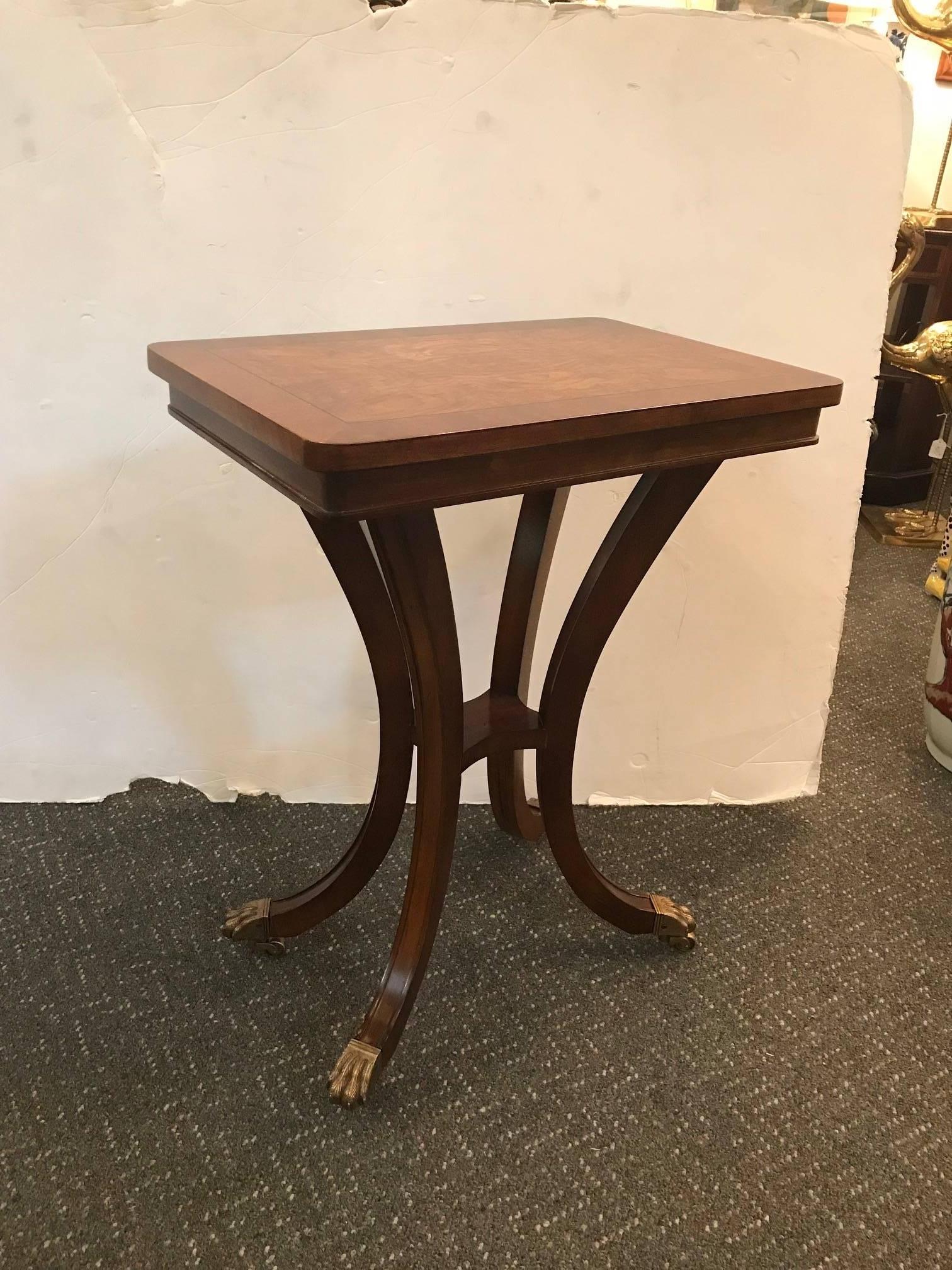 A diminutive pair of neoclassical lamp side tables. The walnut burl tops framed in walnut satin borders supported by graceful saber legs, capped paw feet with castors.
