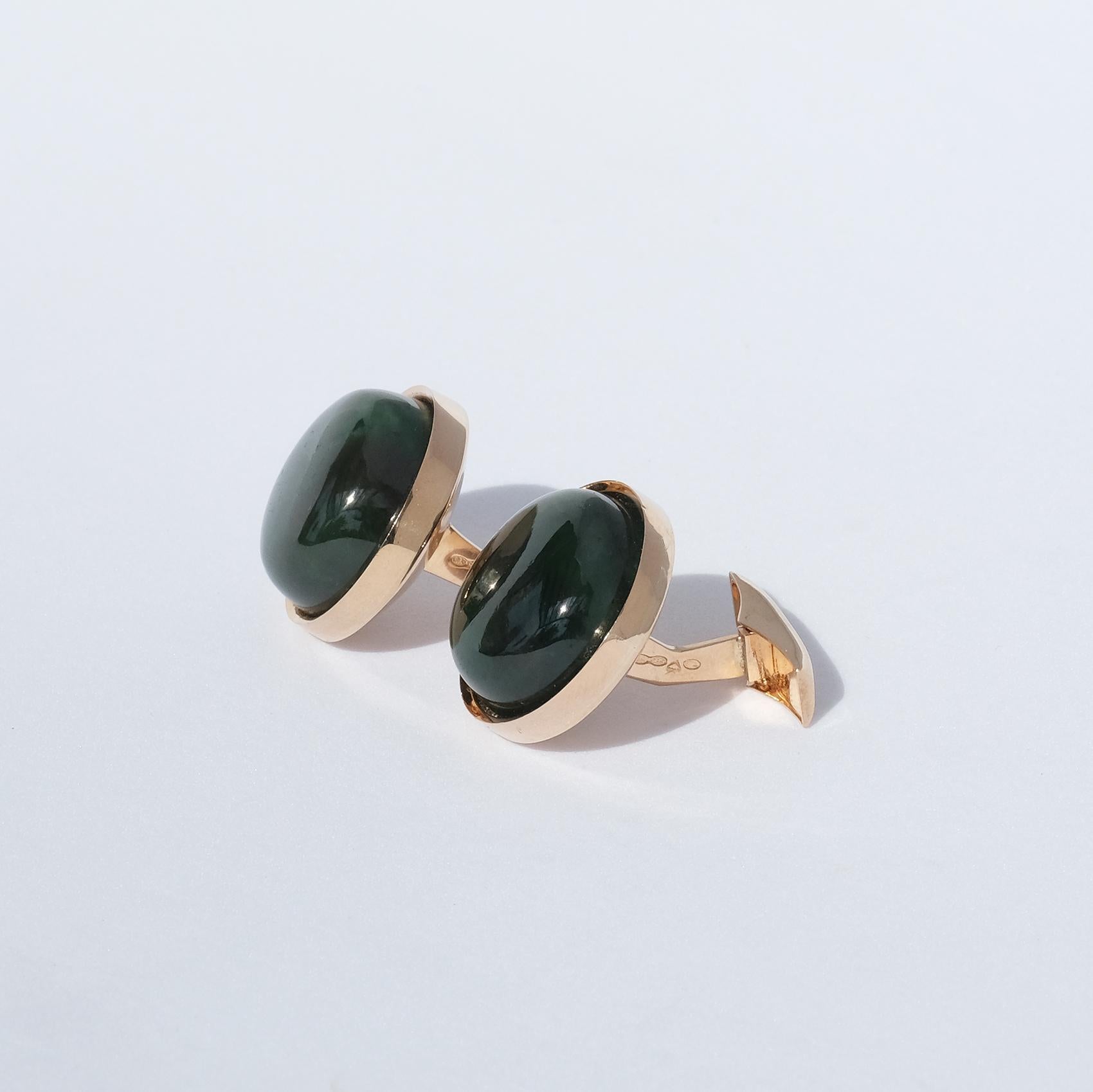 This pair of 14 karat gold and green garnet cufflinks have a round and soft shape. They have a classic look and will work well at any occasion. 