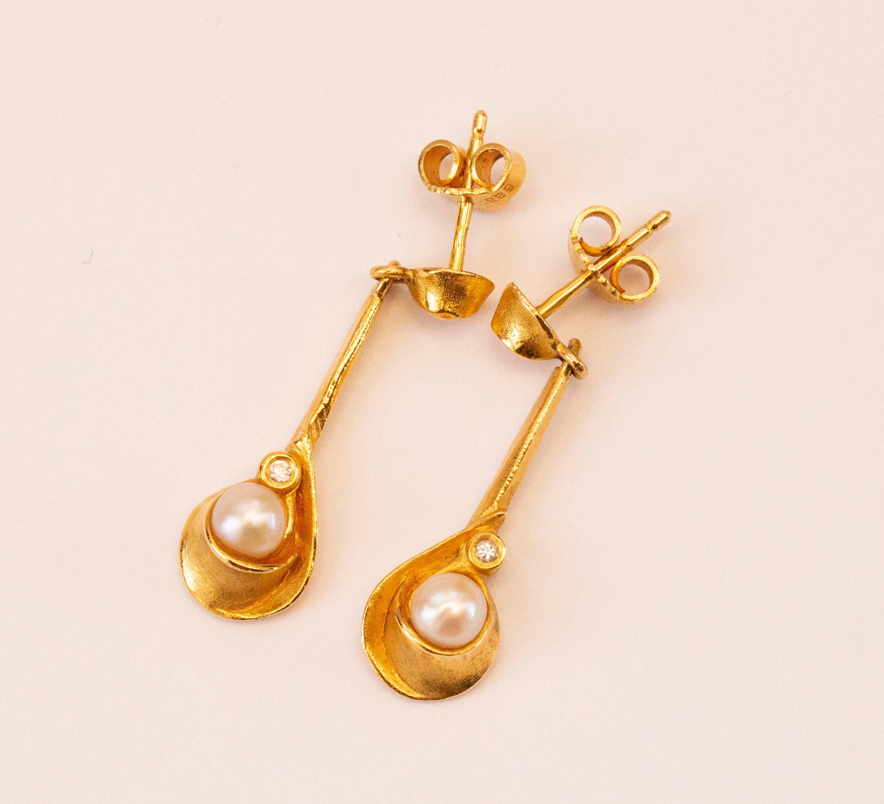 A pair of vintage 14 karat yellow gold earrings with a cultivated Akoya pearl and a diamond. The diameter of each pearl is ca. 6 mm and the  diamond weight in each earring is ca. 0.02 carat.  The surface of each earring is slightly textured that