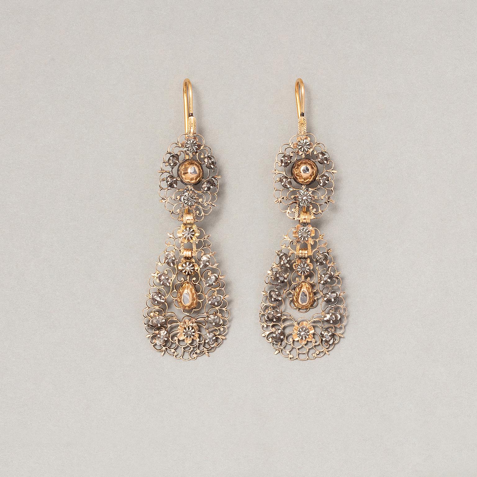 A pair of 15 carat gold and silver Georgian Flemish long earrings, with a lace like design, the earrings have been constructed from gold plate completely open worked with scrolls and flowers decorated with rose cut diamonds set in gold and silver,
