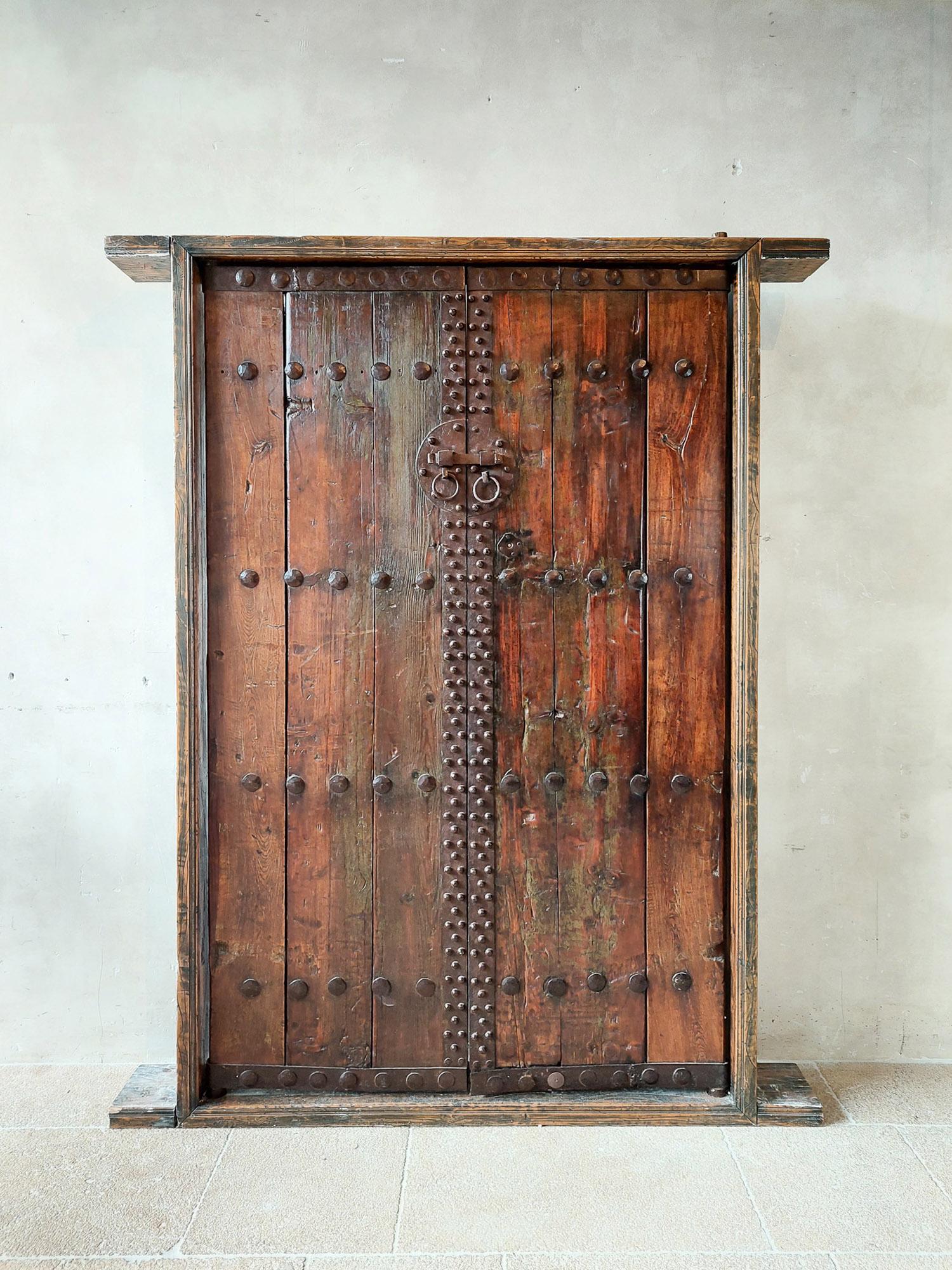 A pair of 17th century Spanish Cortijo wooden doors with doorframe. These antique pine doors in spanish or mexican finca style with wrought iron studs have been completely restored by the previous private owner: the doors have been made wider and