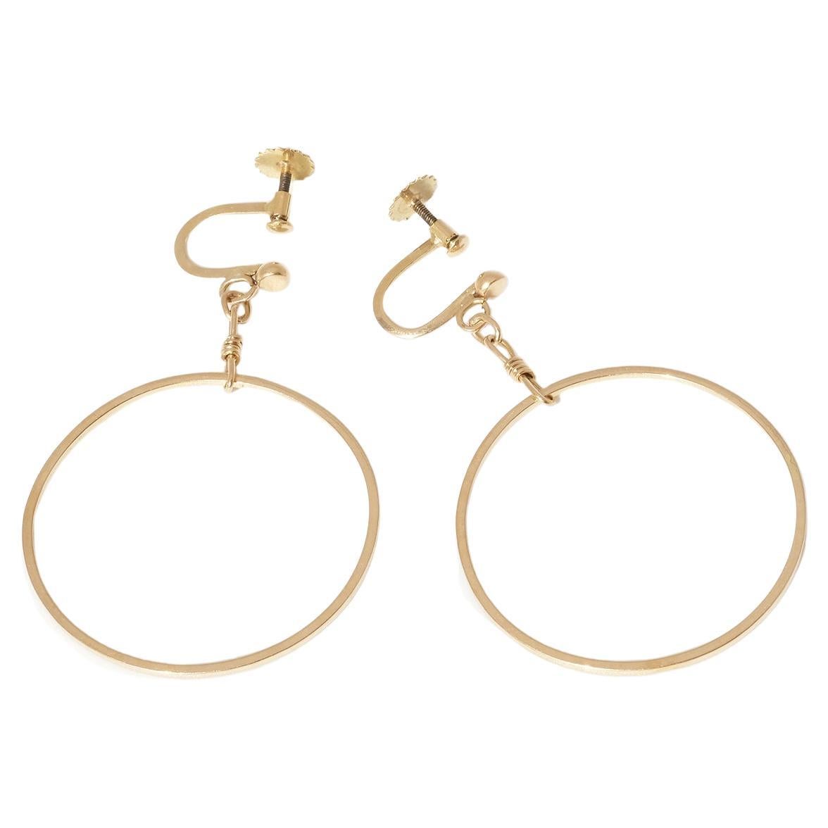 These 18 karat gold earrings are circle-shaped whilst the bar itself is rail-shaped instead of being round. They have so called screw backs, like many of the earrings had during the early 1900s through the 1950s. Between the pendant and the screw