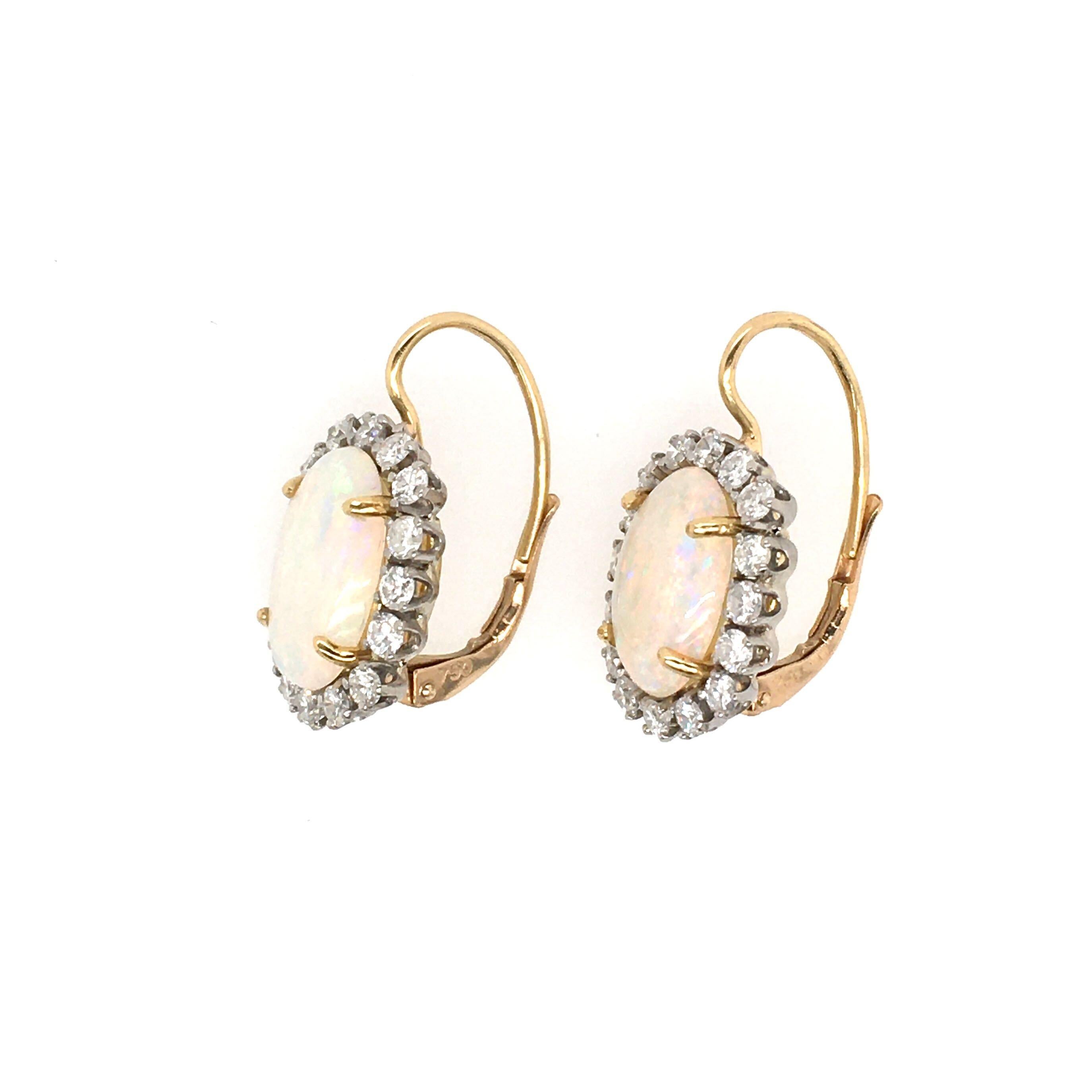 A pair of 18 karat yellow gold, opal and diamond earrings. Set with an oval cabochon opal, measuring approximately 12.0 x 9.0mm, within a circular cut diamond surround, with lever backs. Thirty two (32) diamonds weigh approximately 1.60 carats.