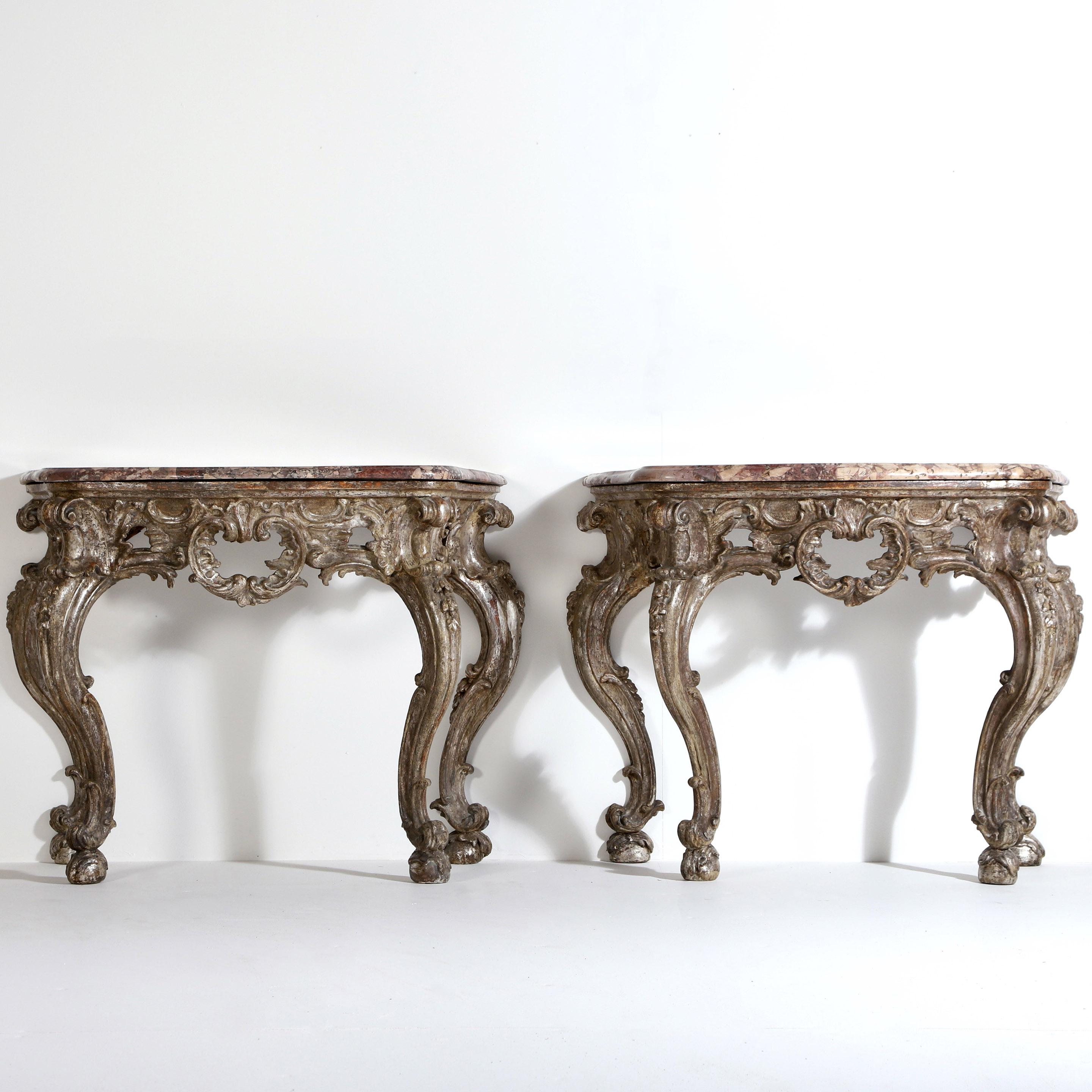 A striking pair of Italian Baroque 18th century console tables in their original silver gilded finish…ageing and fading beautifully to a soft yet stable distressed silver that compliments the bevelled breccia marble tops.

The marble tops