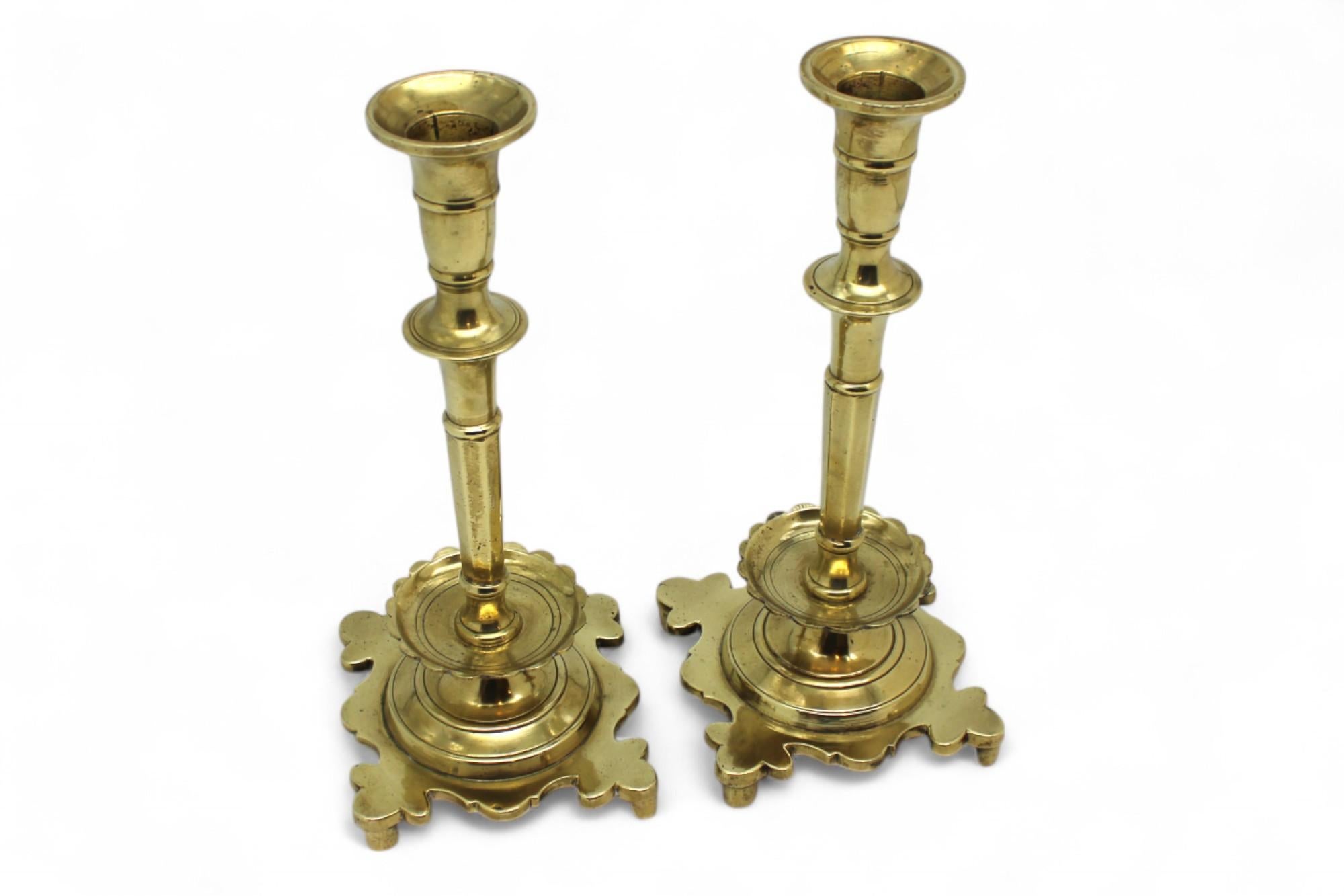 This elegant pair of 18th-century Polish Shabbat candlesticks showcases the refined craftsmanship and stylistic sensibilities of Eastern European Judaica from the period. Cast entirely in brass, each candlestick stands on a bold and sculptural
