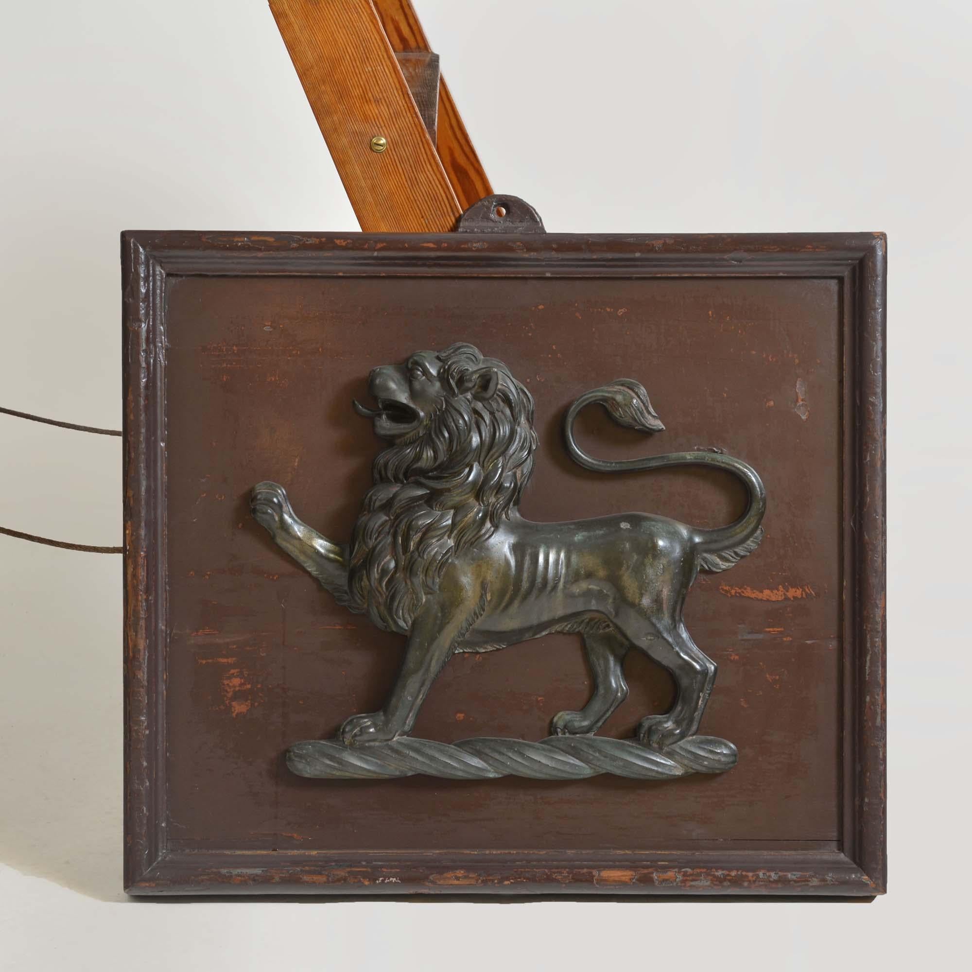 A pair of 18th century cast bronze heraldic crests, in the form of a lion passant, facing dexter, standing on a torse. The patination, condition, detail and quality all suggest the lion dates from the 18th century.  Mounted upon patinated and