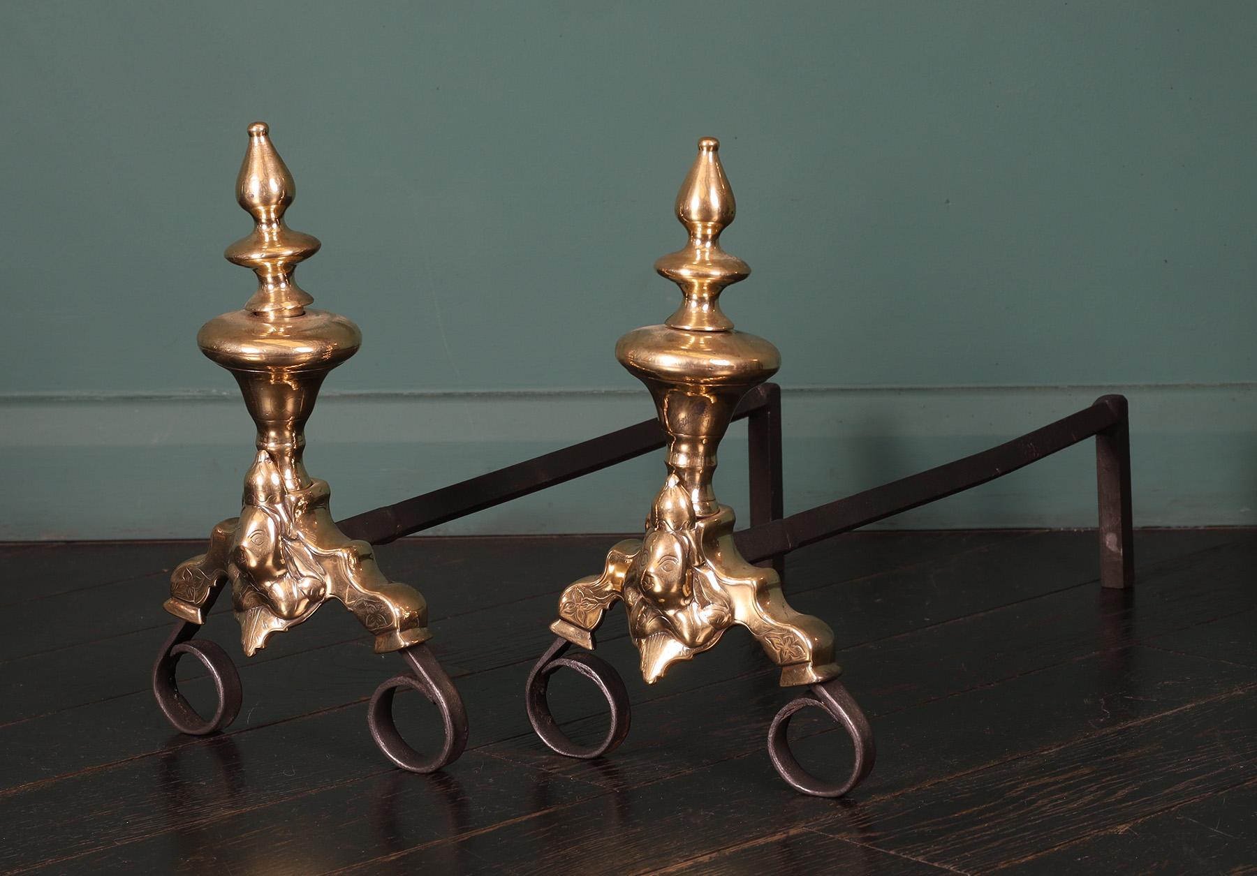 A pair of 18th century Dutch brass and wrought andirons. The vase shaped finials are supported on scroll feet faced with engraved central mask. Restored. 
Circa 1750.