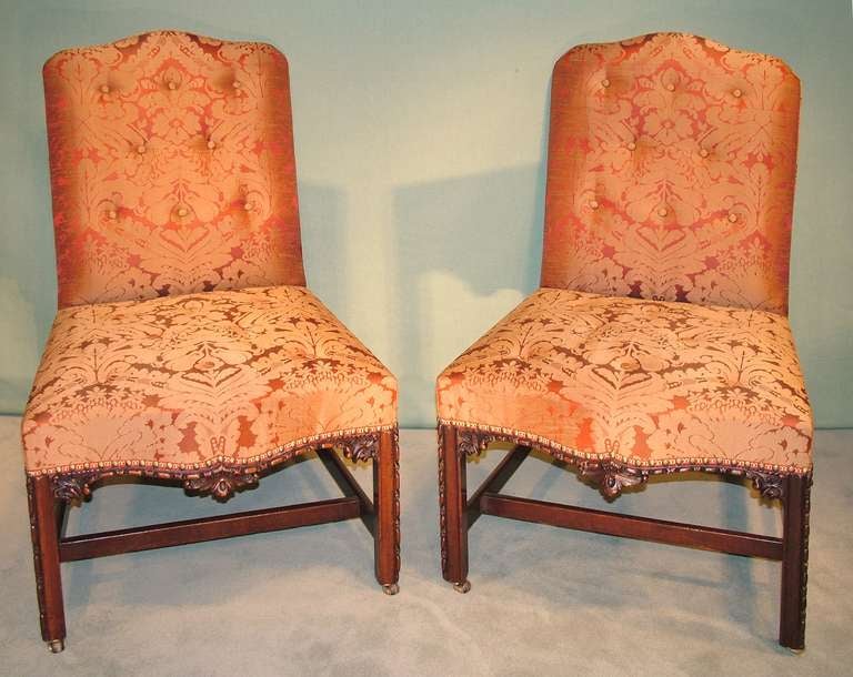 A fine pair of mid-18th century Chippendale period mahogany side chairs with serpentine backs and seats, having stuffover seats with boldly carved decoration, supported on carved square legs with stretchers.