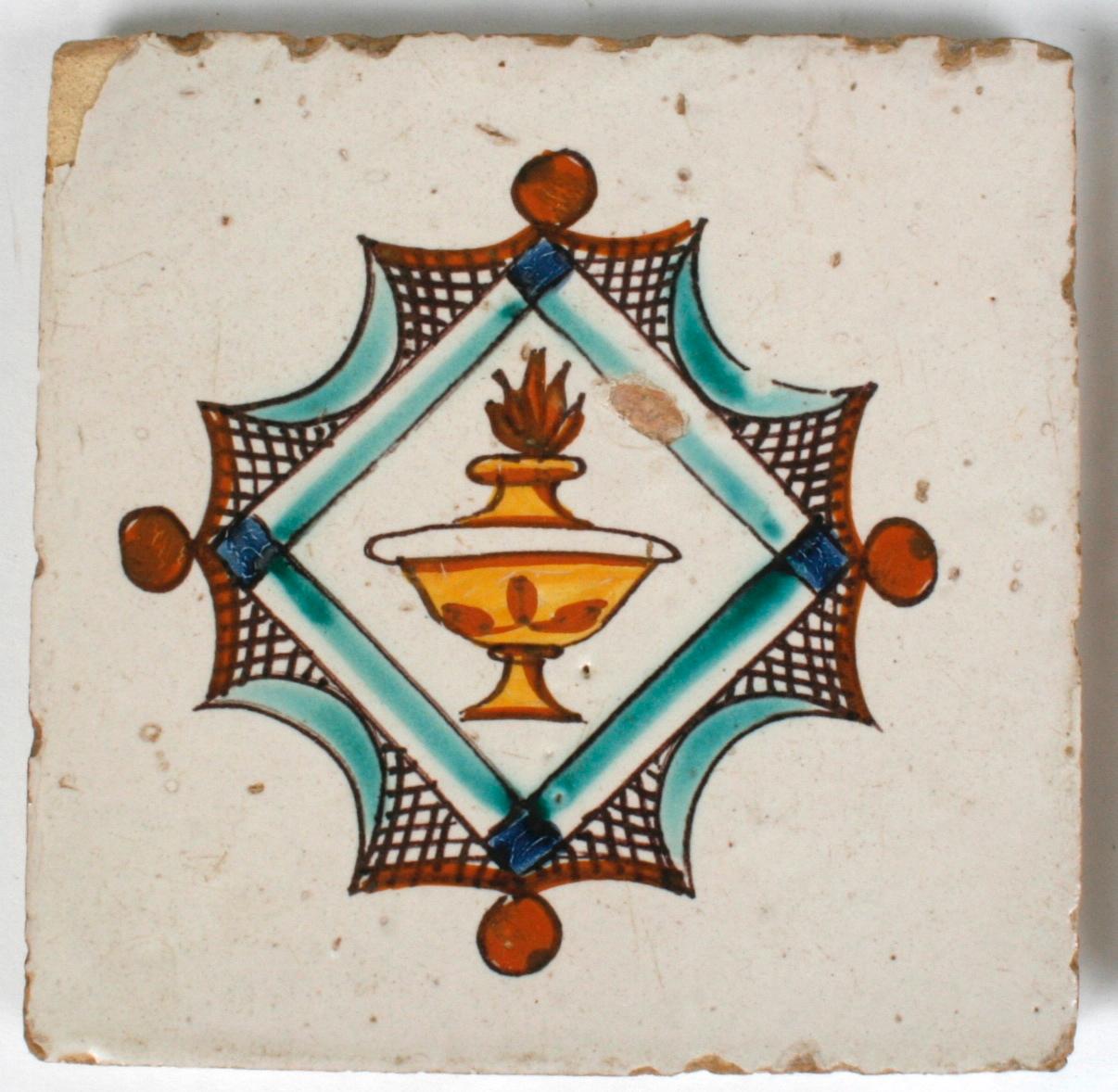 A pair of 18th century hand painted Spanish tiles with a torchiere design. Each measures 5.25