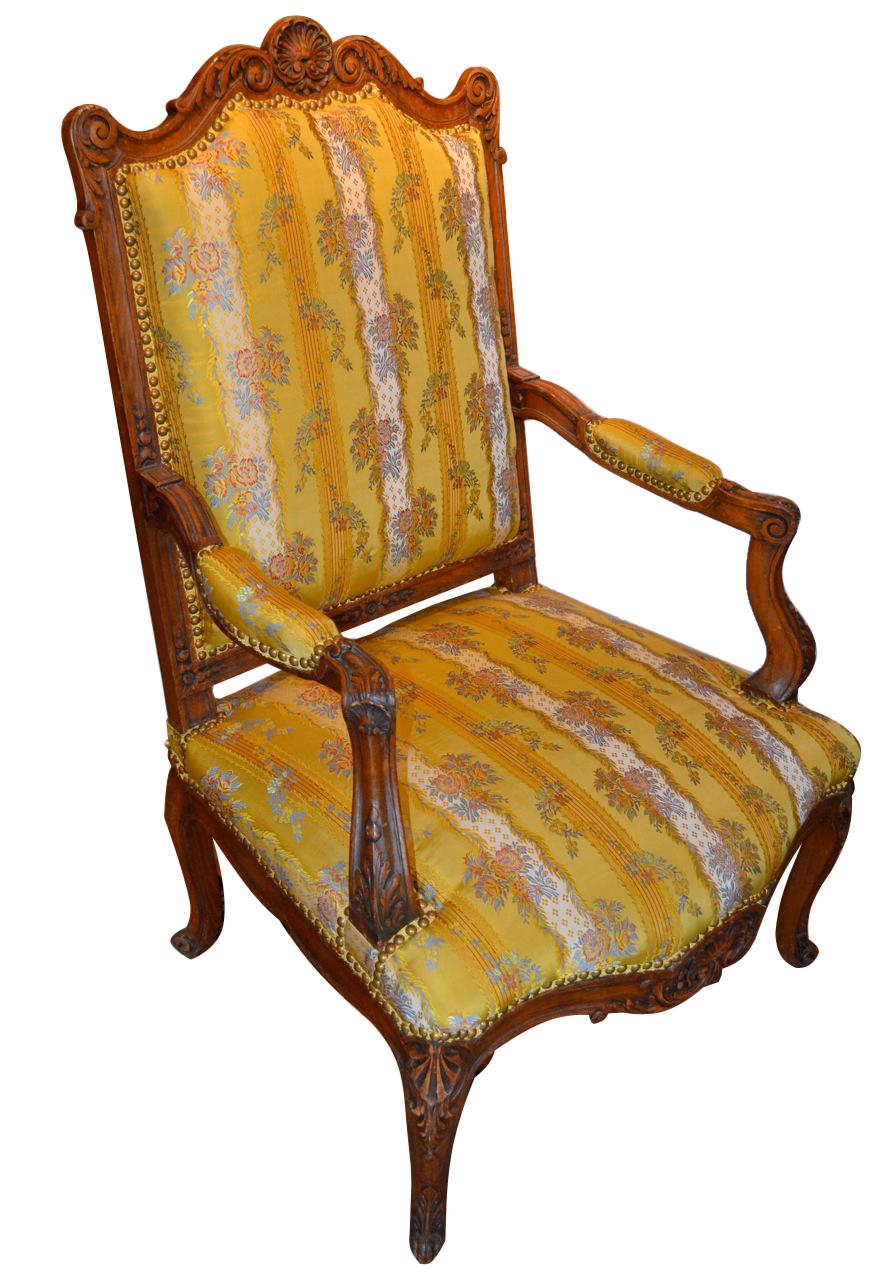 A pair of salon scale Louis XV style open armchairs, the frames in deeply carved stained beechwood. The back of the chair is slightly reclined. The shaped back/top with rounded shoulders has a large carved shell in the middle flanked with scroll