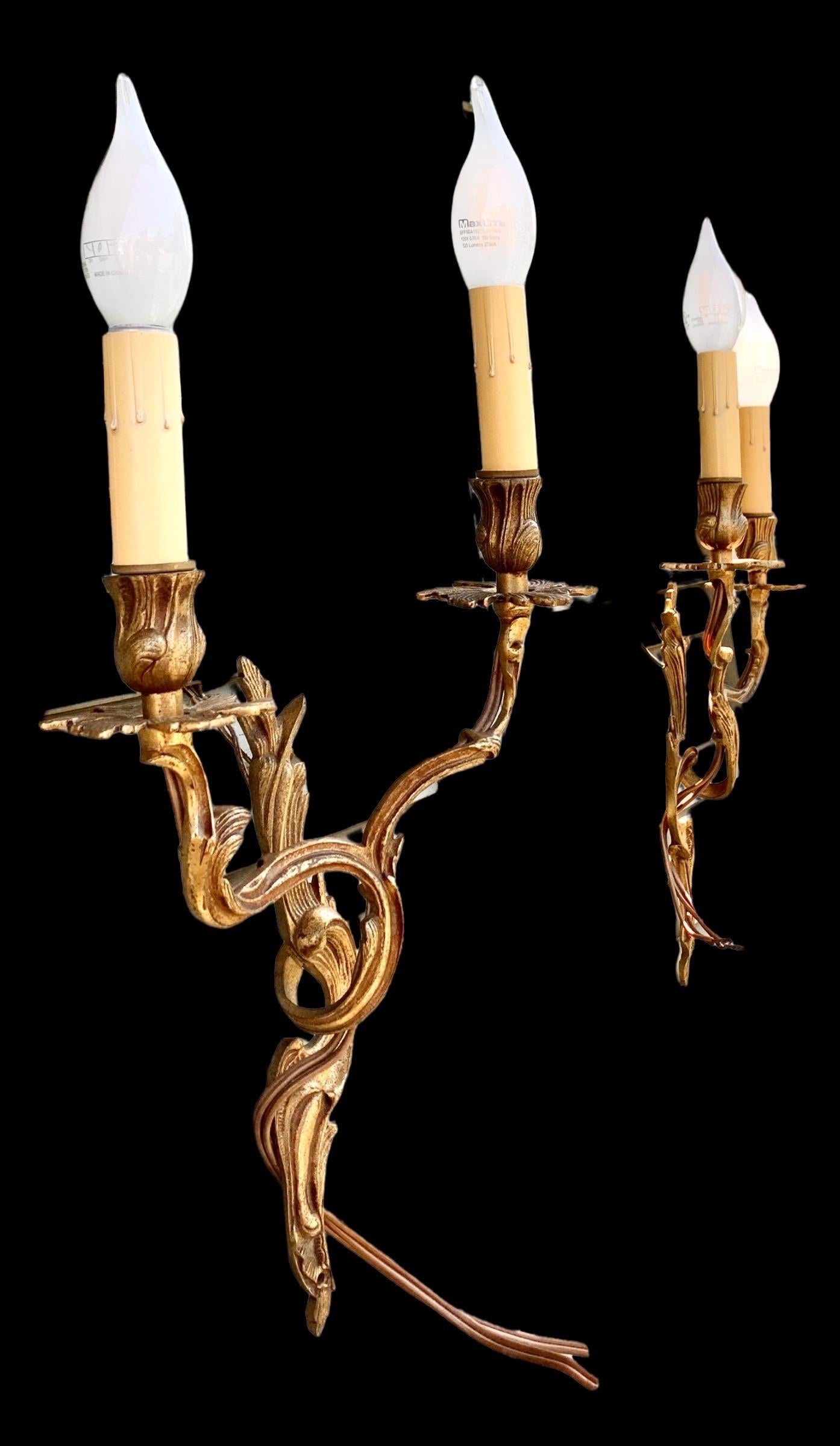 A lovely pair of Louis XV style gilded bronze electrified wall sconces. The flowing floral design is indicative of the high Louis XV style in France although these were created in Spain for the French market. 

Use these in your foyer, dining