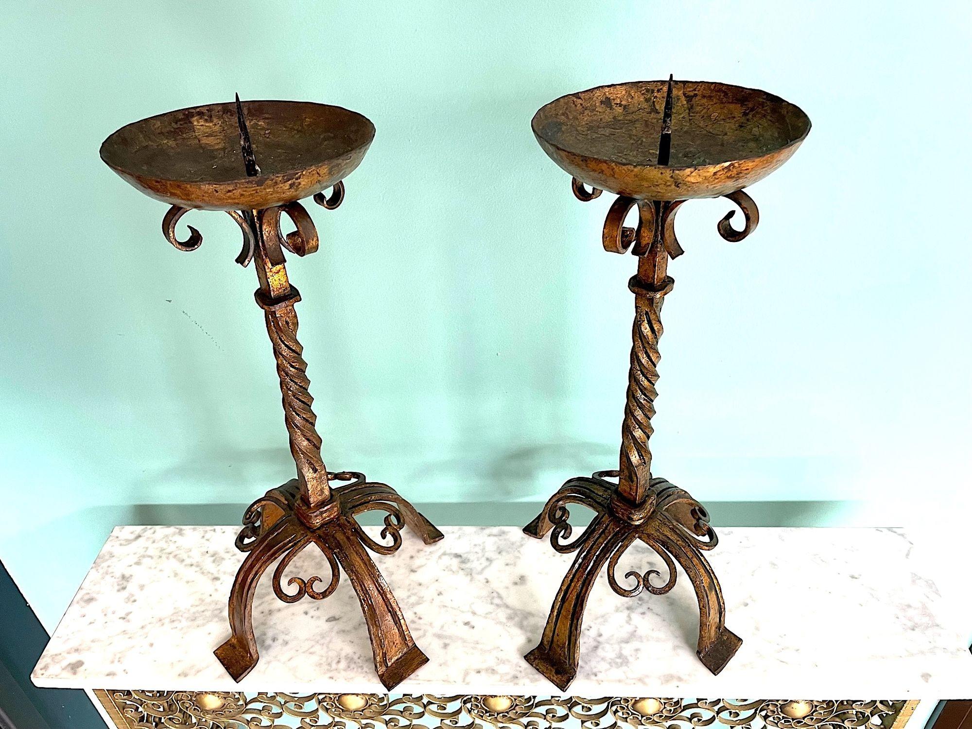 A pair of 1920s Spanish ecclesiastical gilt wrought iron candle sticks, each with ornate barley twist stem, scrolling and turned feet. 
OrigIn: Spain
Date: 1920s
Dimensions:
Height: 53 cm
Width:  26.5 cm
Depth: 26.5 cm
Condition: Good orignal