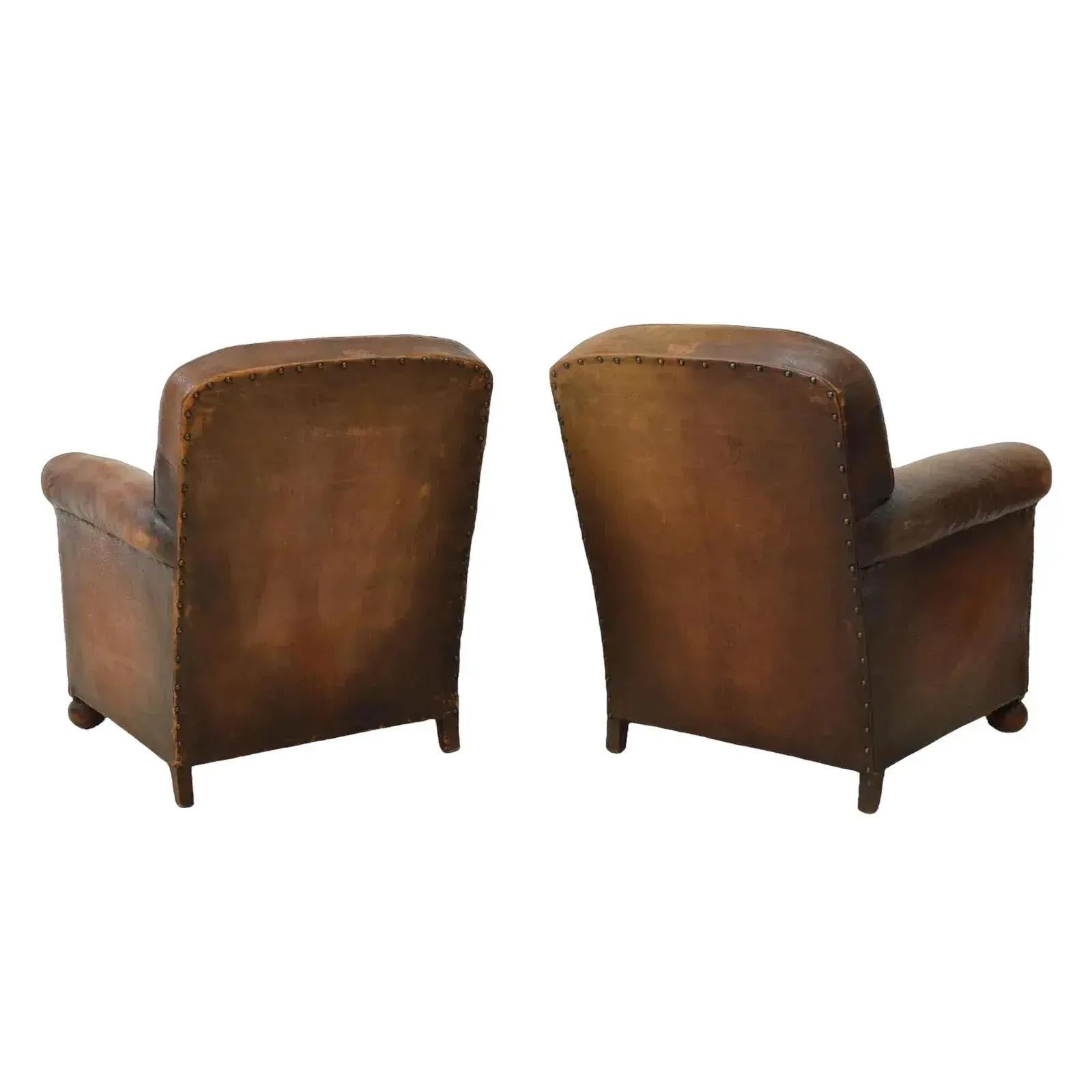 French Art Deco leather club chairs, c.1930s-1940s, rounded back, iron tacks, velvet upholstered loose seat cushion, rolled arms with piping trim. They rest on ball feet and are worn with some leather loss. They have a beautiful, rich patina.  There