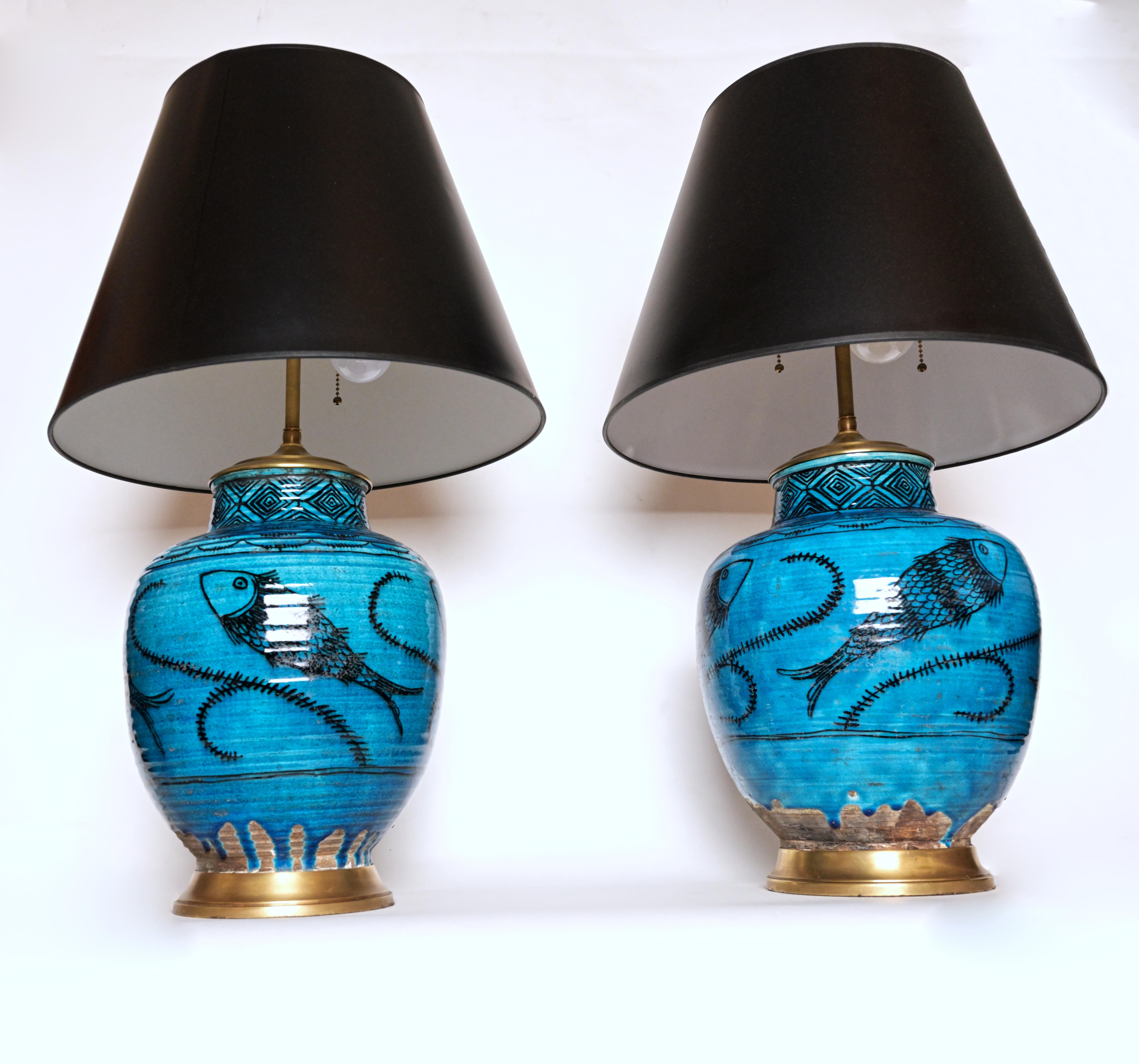 A pair of 1930s French salt glazed vases based on antique Syrian designs depicting stylized fish with seaweed motifs the upper section with black geometric motifs each face with signature dripping gaze at base revealing unglazed ceramic form. Vases