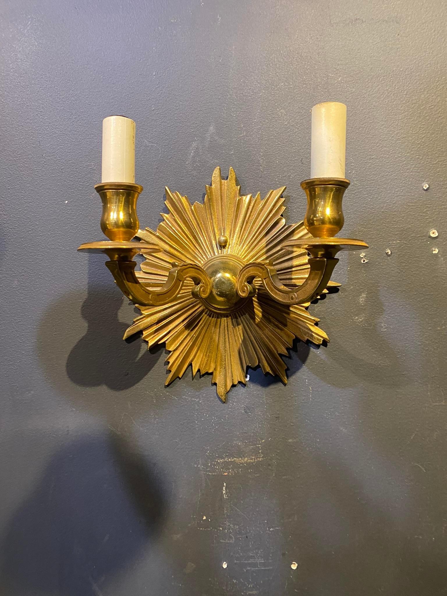 A pair of circa 1920's French gilt bronze sunburst double light sconces.