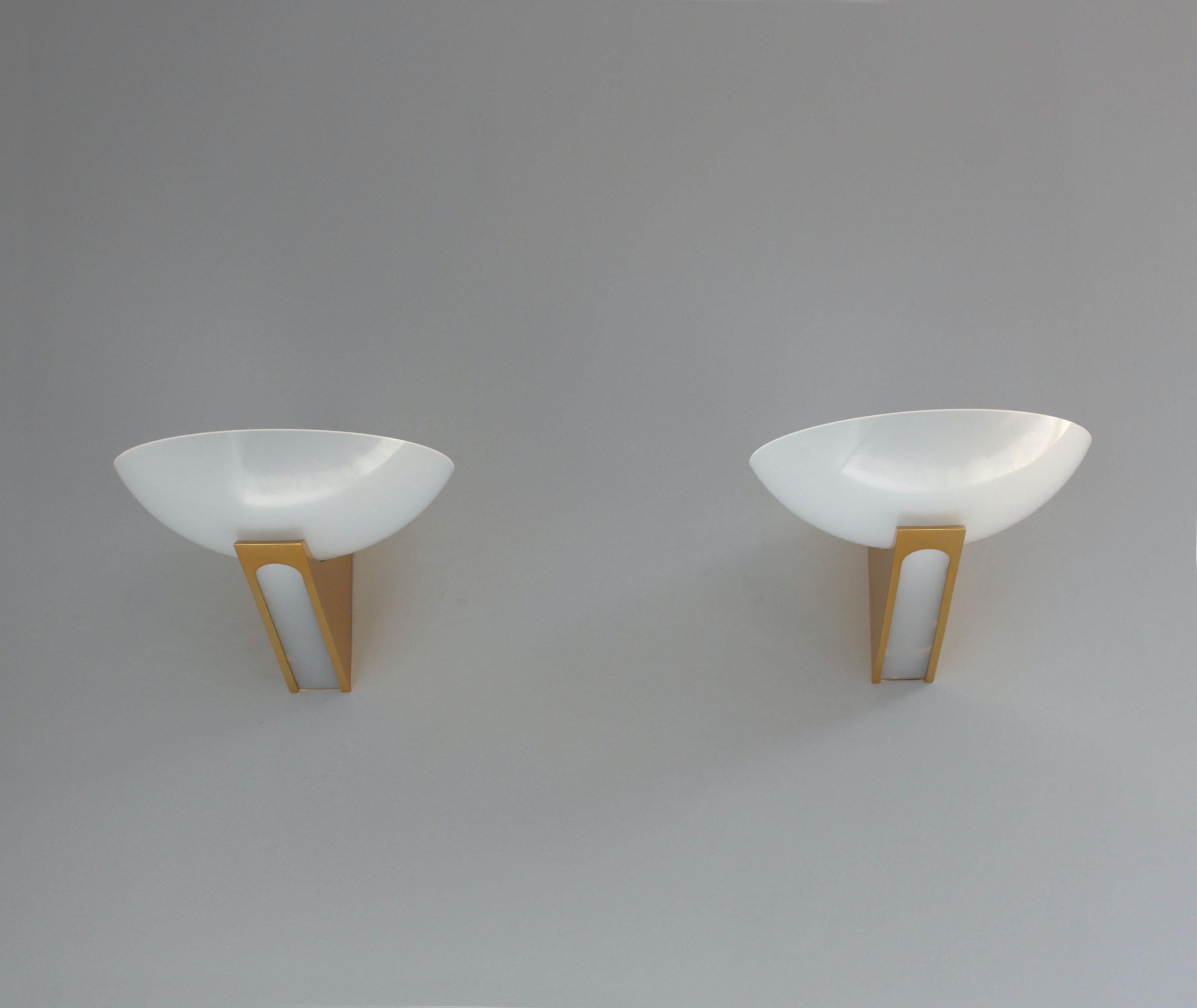 A fine pair of Mid-Century wall lights with polished brass mounts with cutout reveals, supporting lucite bowl-shaped shades.