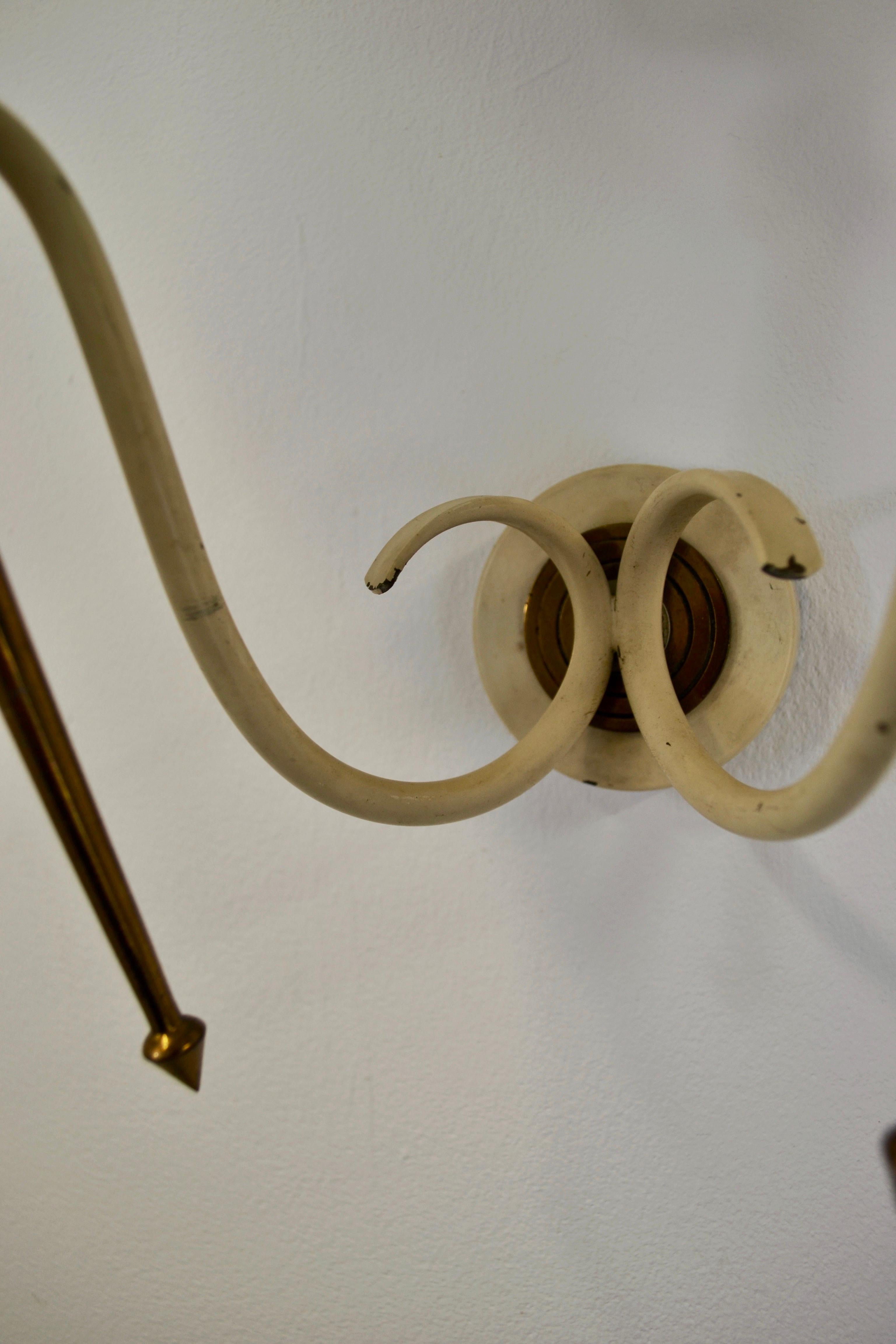 Cette étonnante paire d'appliques murales des années 1950 combine d'élégants éléments en fer formé et en laiton, apportant un style rétro raffiné et intemporel à votre décoration. Les abat-jour ont été remplacés et sont flambant neufs, prêts à