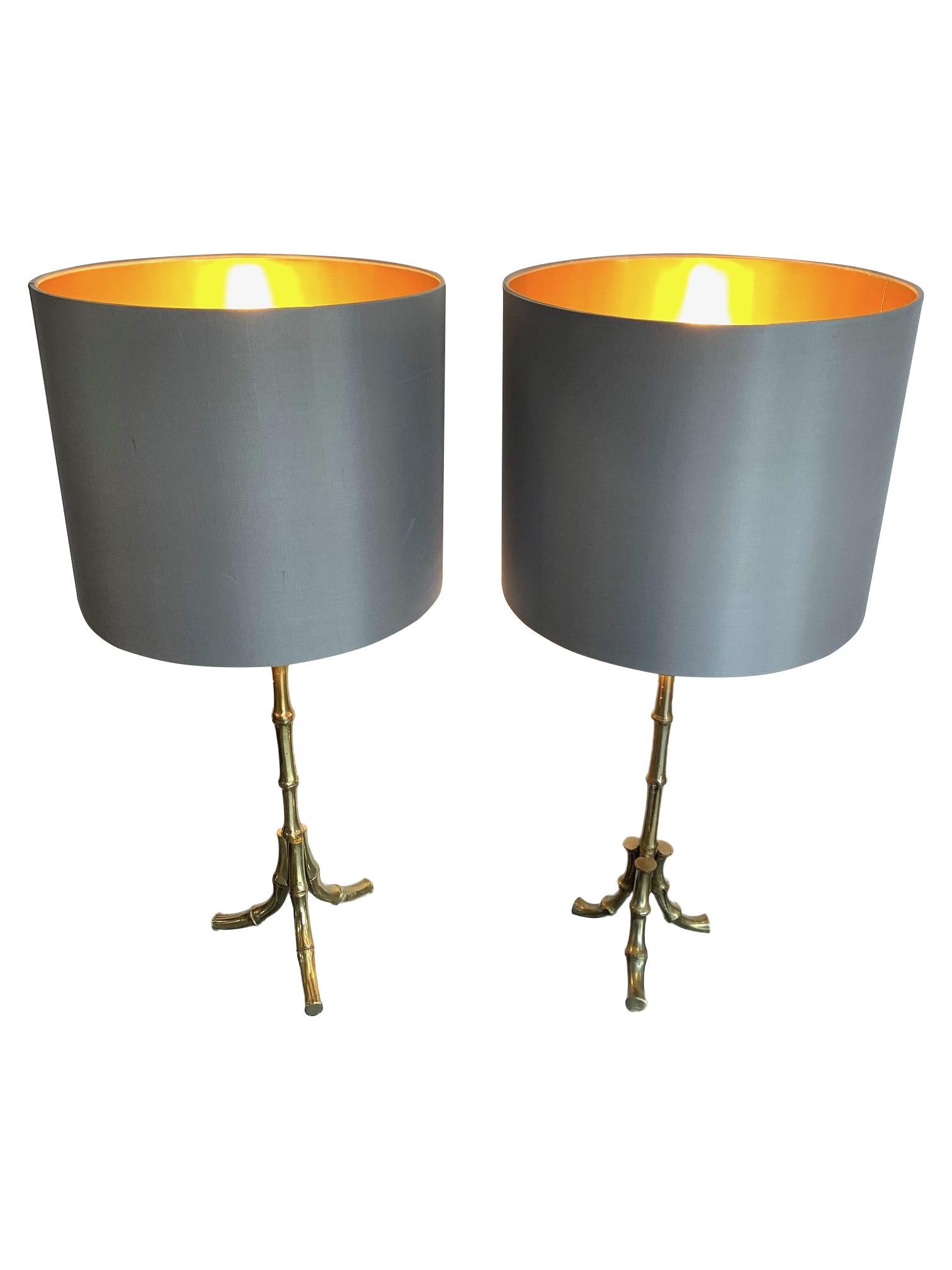 A pair of 1950s Maison Baguès brass faux bamboo table lamps each with three splayed legs. There is a slight variation on the finish on the top of the legs, as possibly one is a variation on the design, rewired with new brass fittings, antique cord