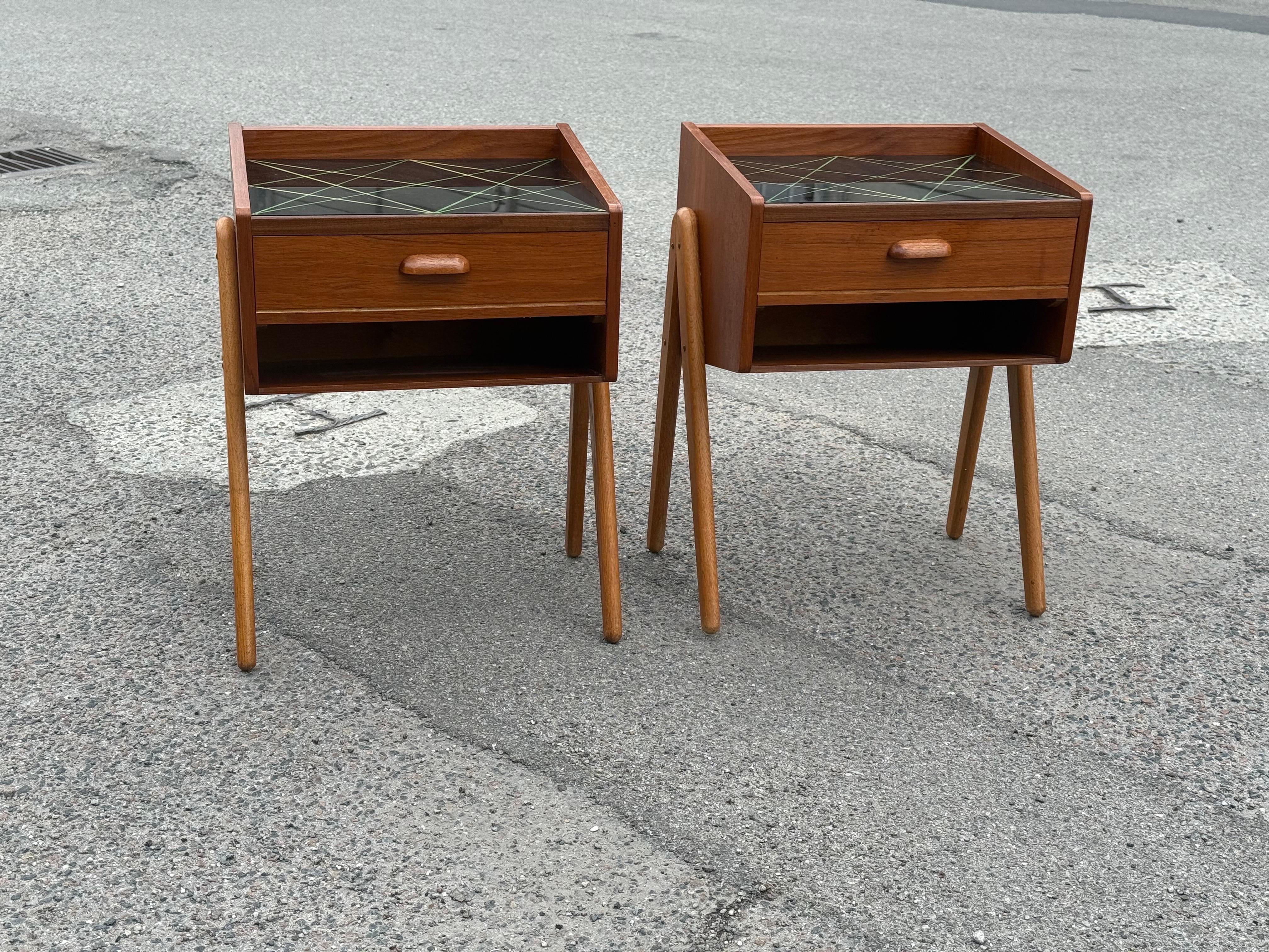 Teck Paire de tables de nuit des années 1960 en teck avec pieds en Oak et plateau en verre décoré en noir en vente