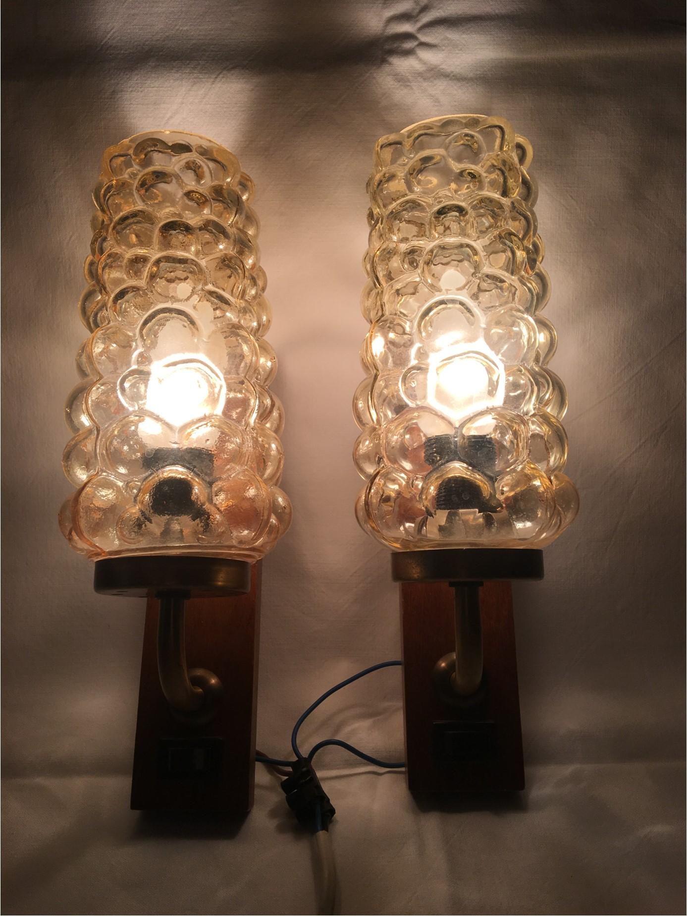 A set of lovely Helena Tynell style bubble glass sconces. Mounted on a petite wooden base with on and off switches. The copper arm is crowned with a pretty bubble glass cover producing lovely lighting effects. Each fixture requires one European E 14