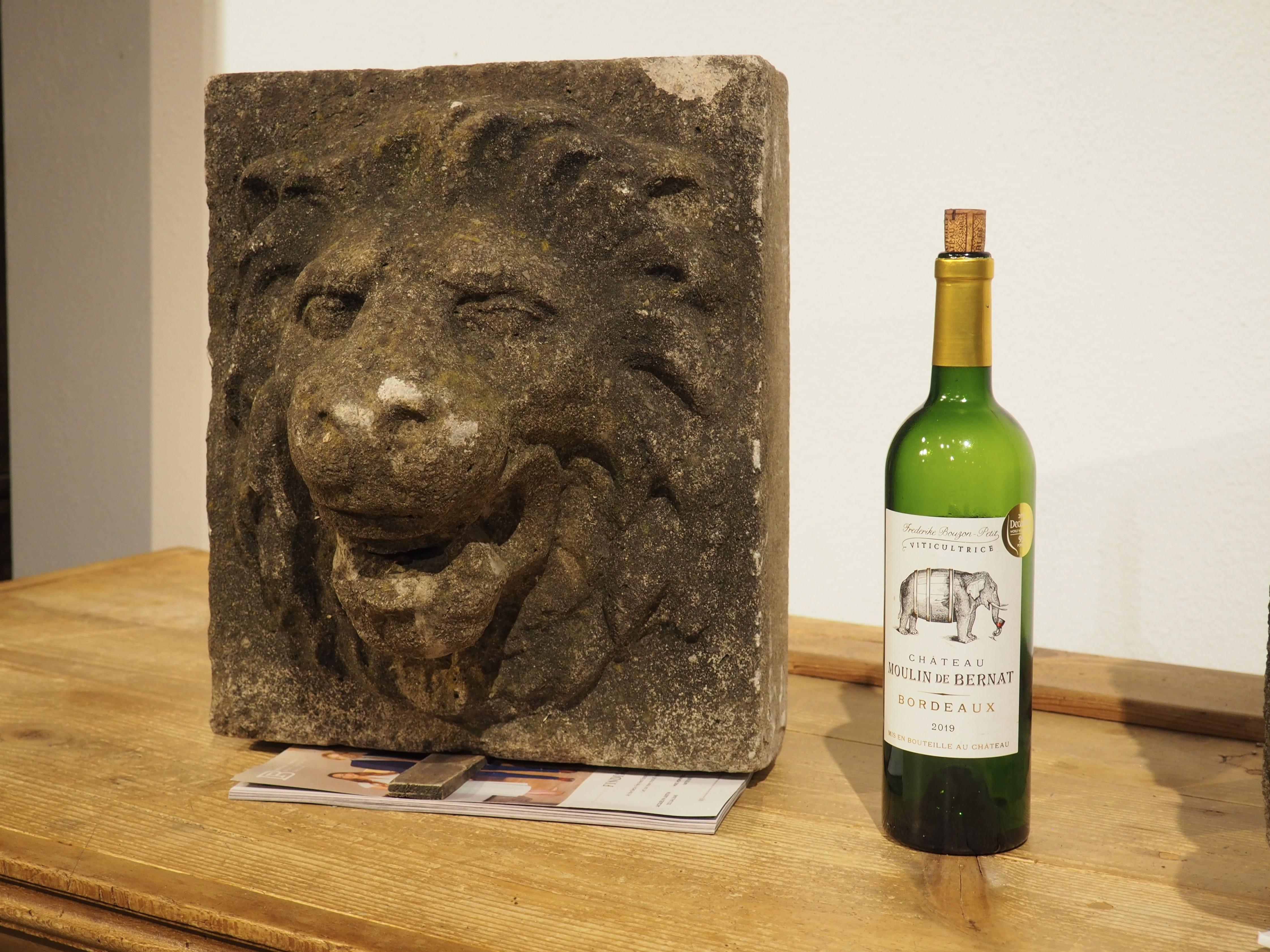 This thick pair of cast stone lion mascaron fountain spouts are from England and date to the 1960s. Cast stone is an aggregate of crushed stone and concrete, in this case, mixed with a stone gray coloring agent that gives the lions their color.