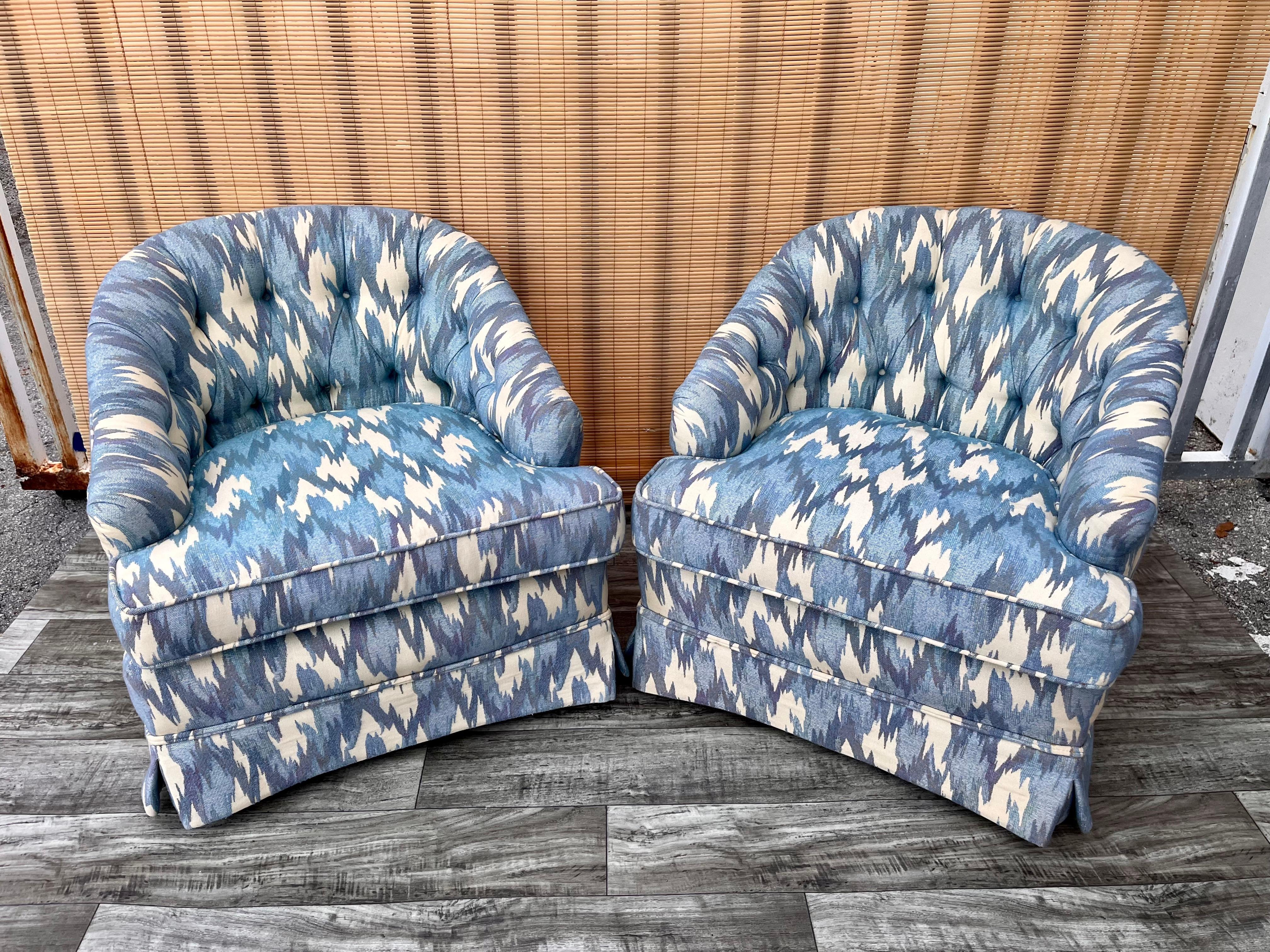A pair of Vintage Hollywood Regency Upholstered Lounge club chairs with casters. Circa 1960s
Feature solid wood frames, barrel backs, original white and blue tufted upholstery, removable seat cushions, skirted bases, the original label, and two