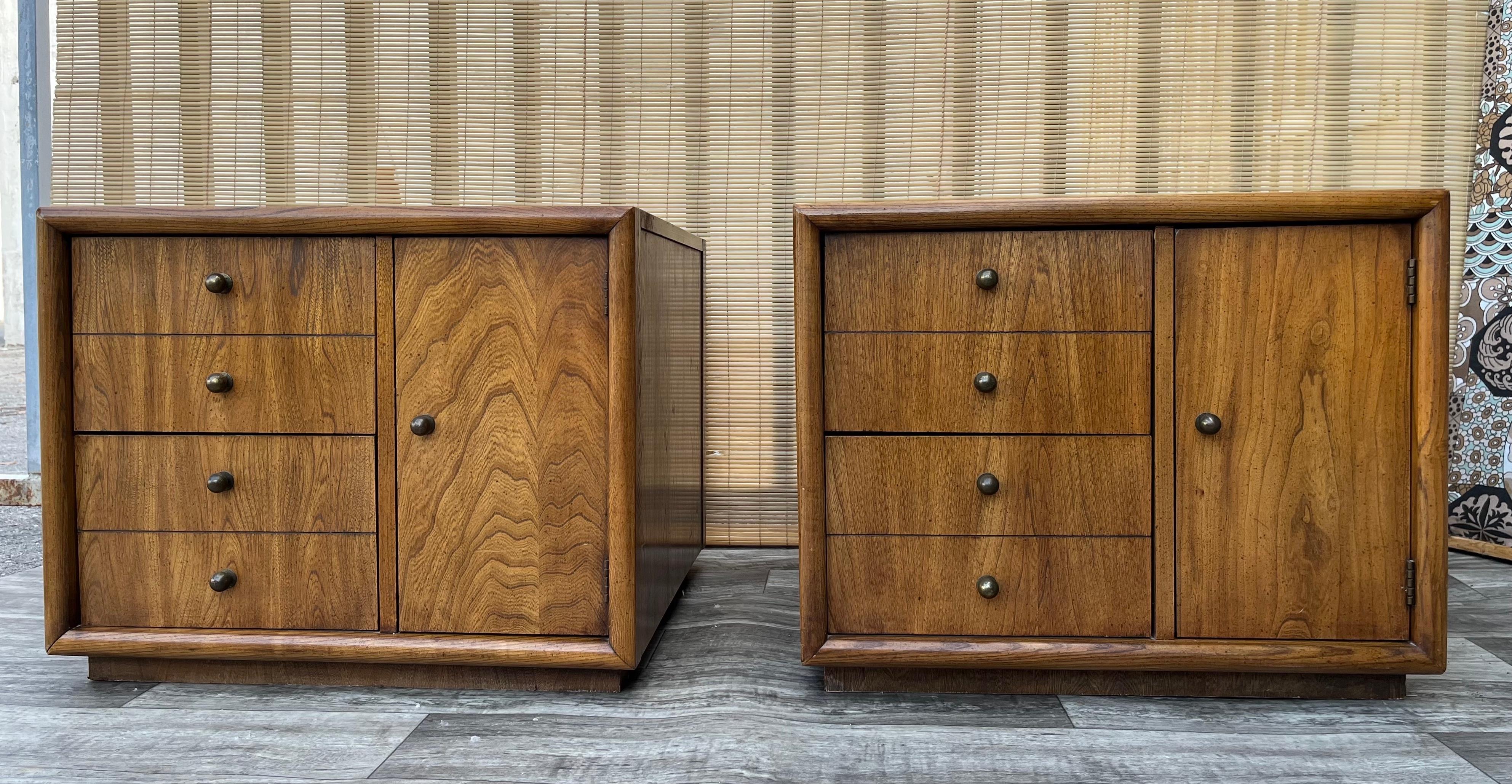 A pair of Vintage Mid-Century Modern Side Tables or Nightstands by Stanley Furniture. Dated 1965
Feature a beautiful walnut wood grain and two drawers and a side cabinet with round brass hardware. 
In excellent original condition with very minor