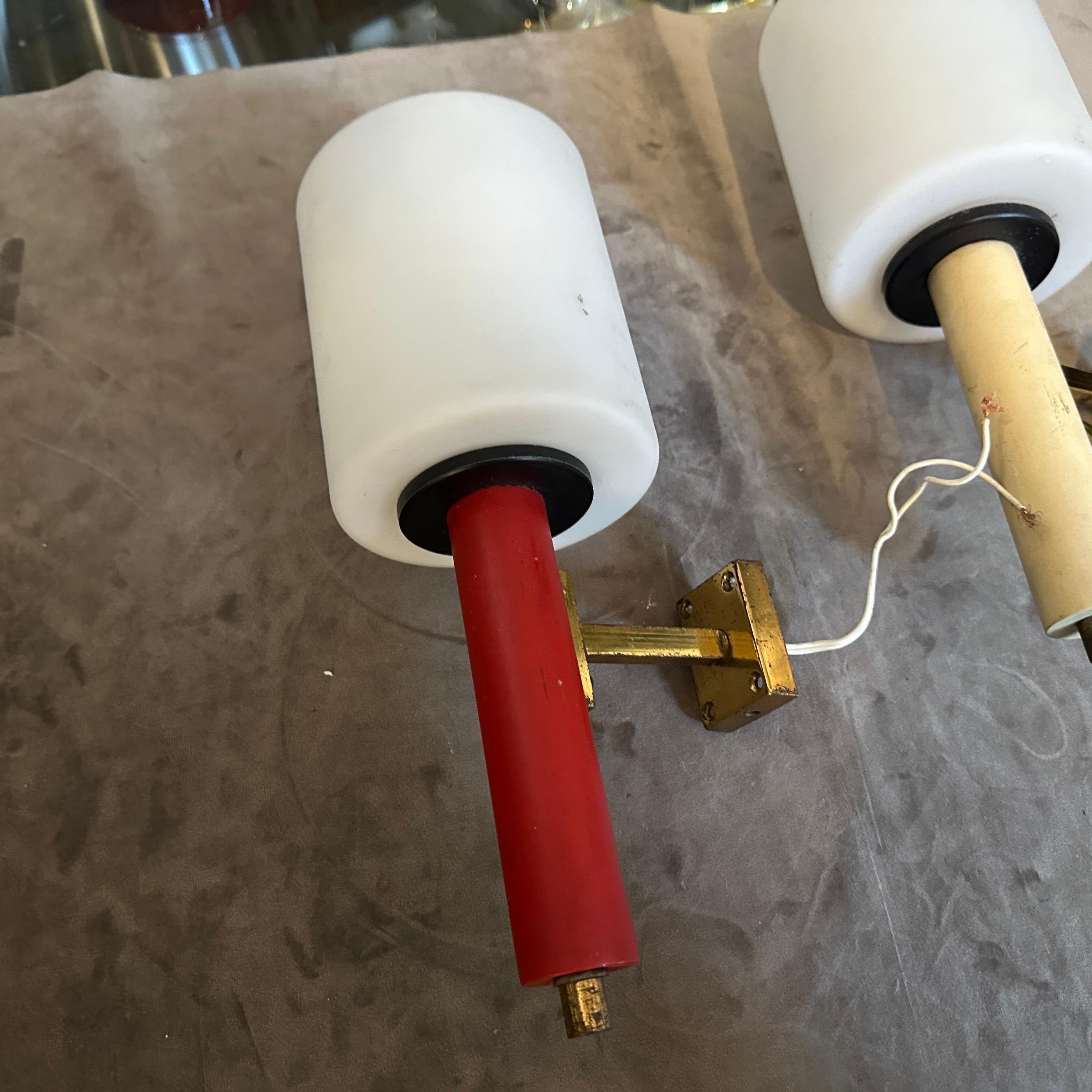 Two brass painted metal and white opaline glass diffusors designed and manufactured in Italy in the style of Stilnovo. The sconces are in different colors, brass it's in original patina and glasses are in perfect condition, normal signs of use and