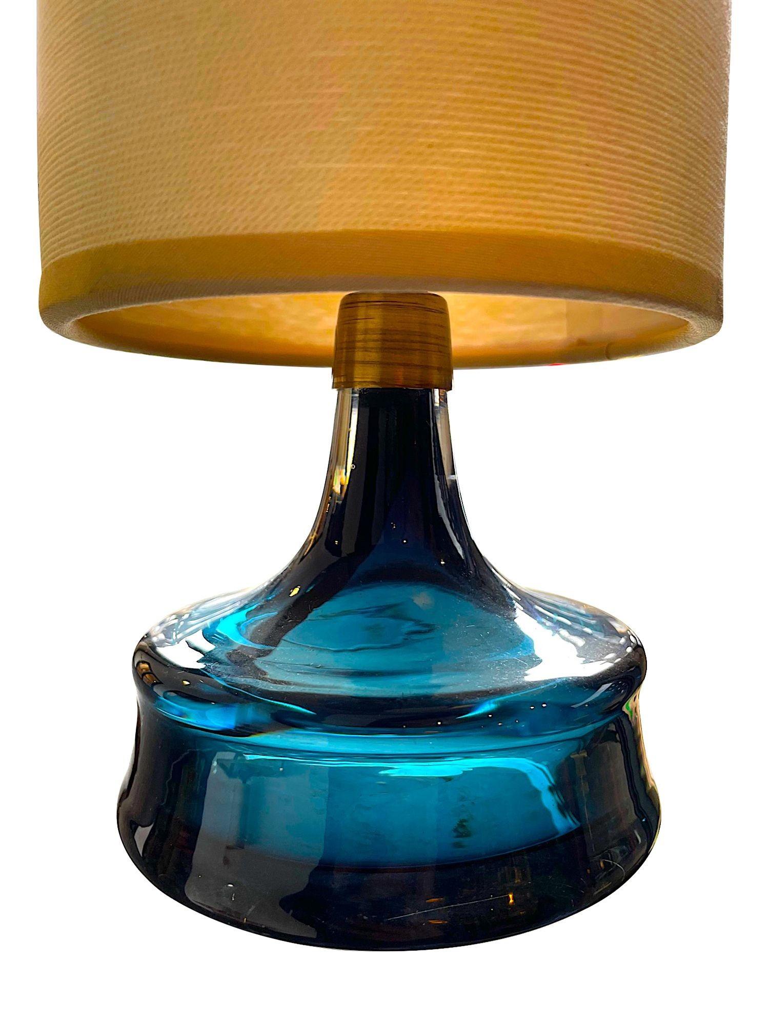 A pair of 1960s Swedish Orrefors blue glass lamps with brass collar and original shades.