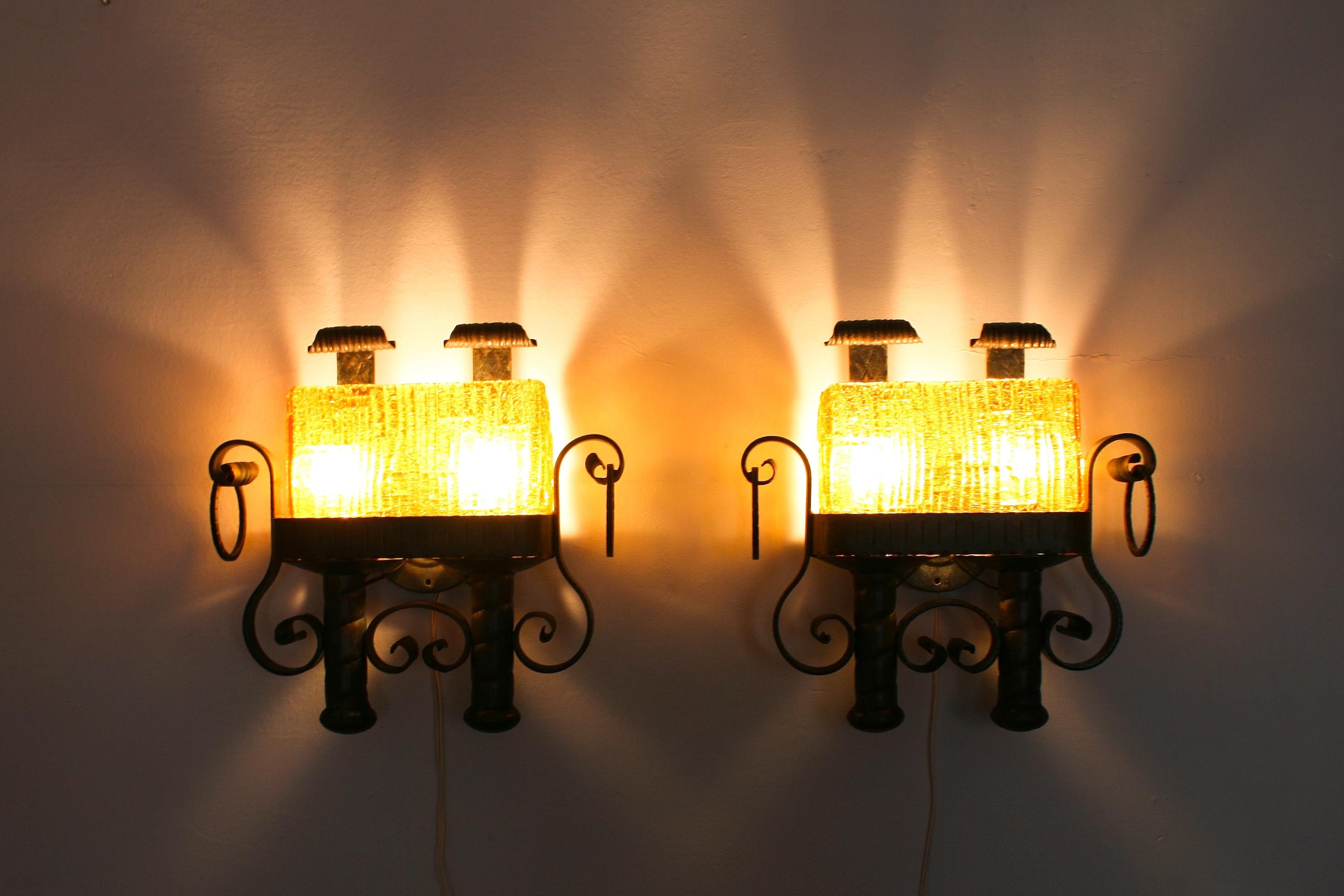 A pair of patinated wrought iron sconces with honey amber colored glass diffusers.

Each sconce had two E27 sockets.