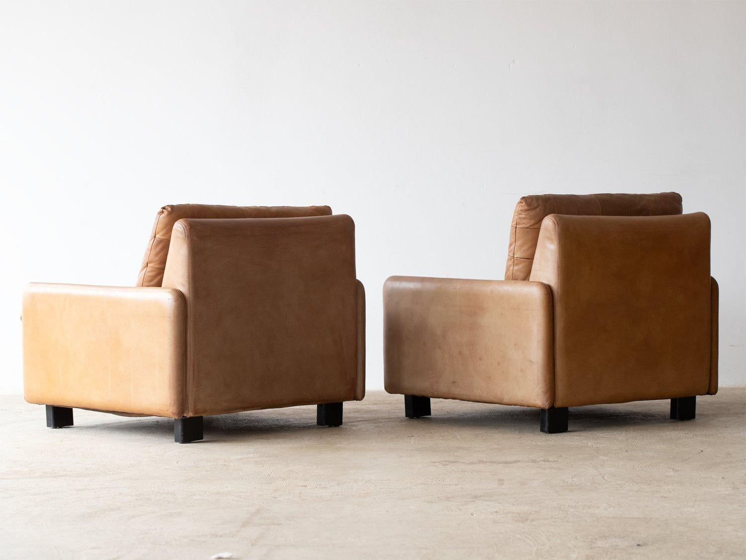 A sublime pair of Italian tan leather armchairs, patchwork leather seat cushions with original small back support cushions.
The tan leather is a perfect mid-century tone with a beautiful patina.
The chairs stand on short black wooden legs with