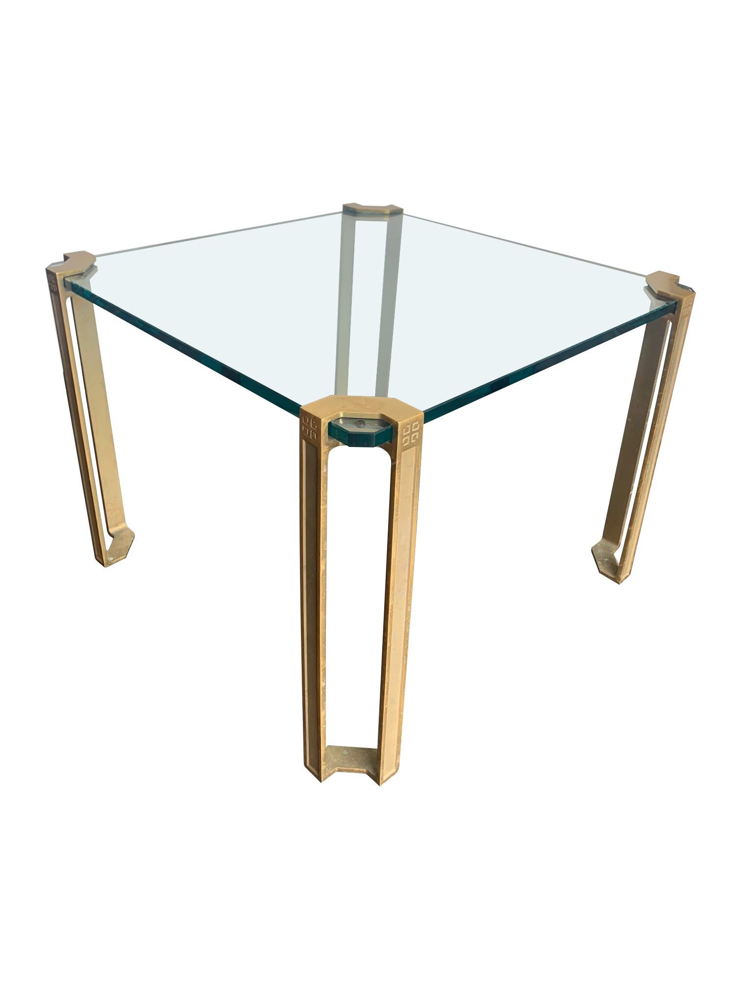 A pair of 1970s Peter Ghyczy brass and glass side tables each with brass corner legs each with the Peter Ghyczy logo design at the top of each leg, fixed to a thick 18mm glass plate.