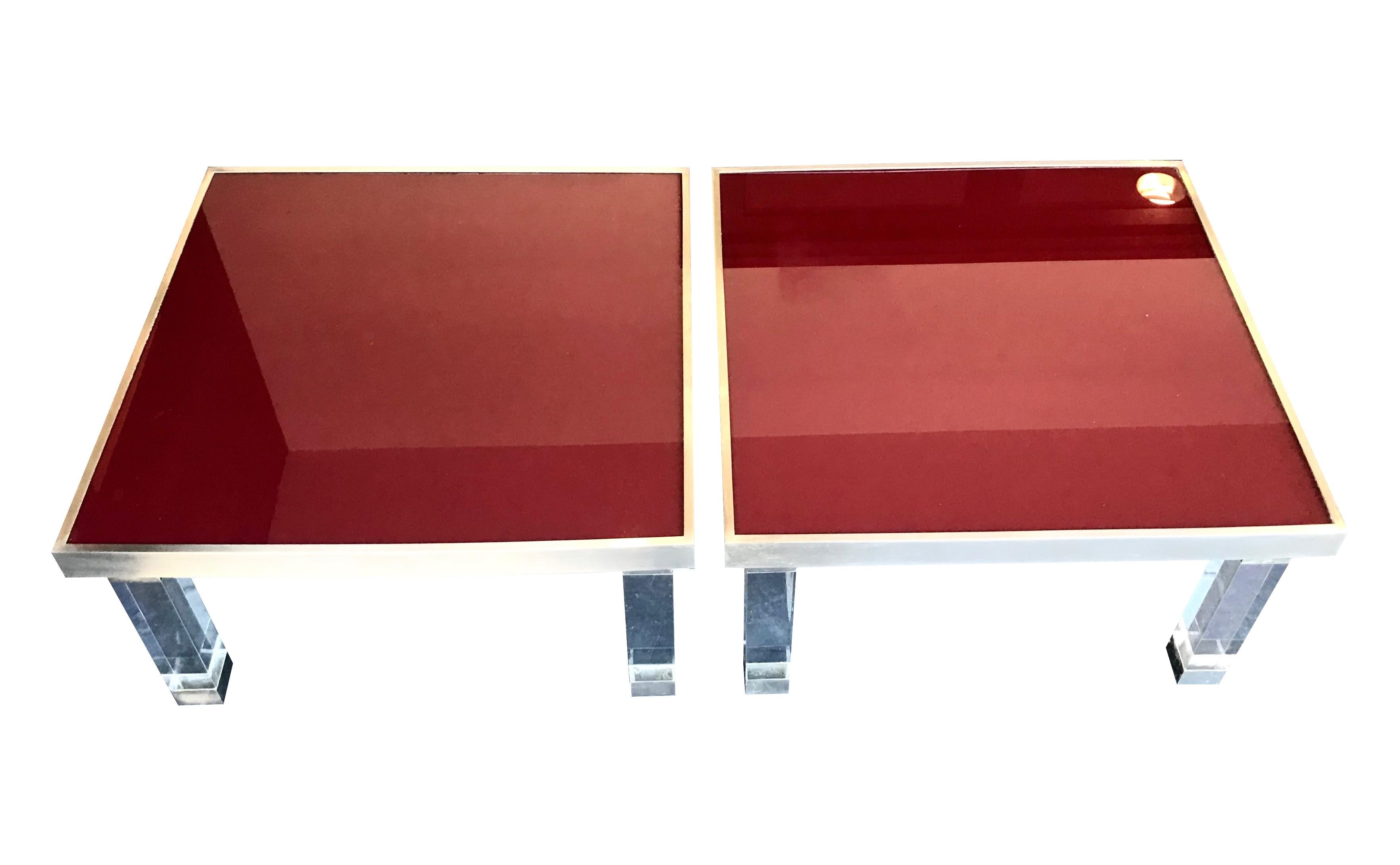 A fabulous pair of 1970s red glass topped topped side tables with solid lucite legs with brushed metal edging and feet. 