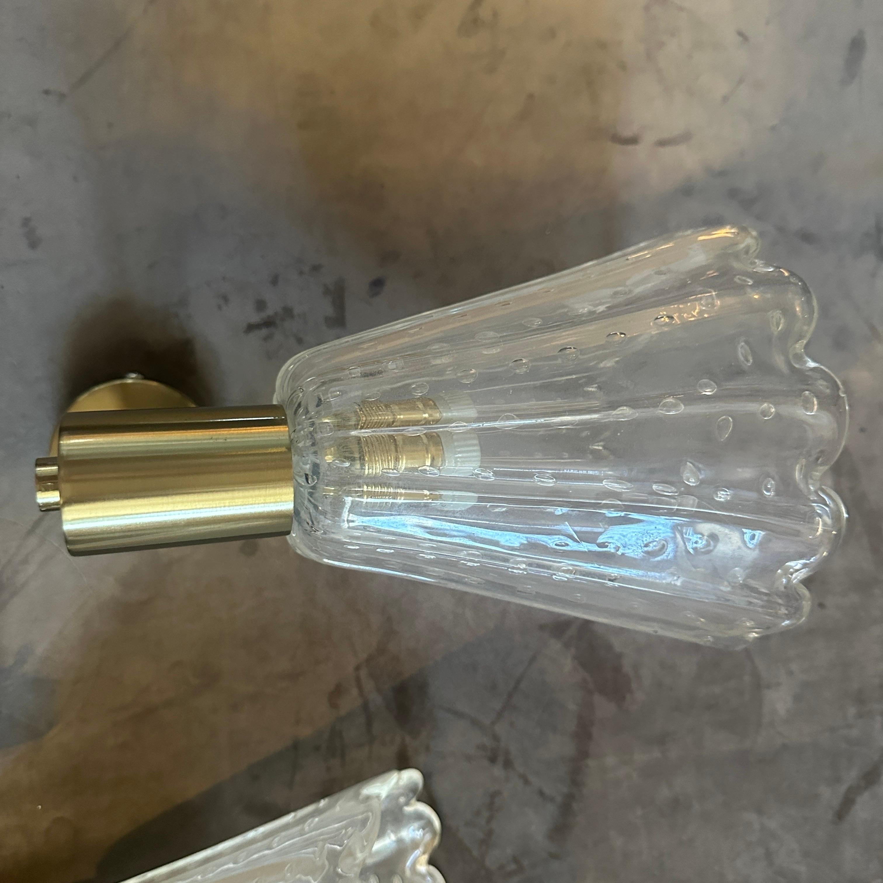 Questa splendida coppia di appliques è caratterizzata da paralumi in vetro di Murano in stile Barovier con la classica tecnica del Bullicante, in cui piccole bolle d'aria controllate sono sospese nel vetro chiaro e scanalato. Le tonalità evocano una