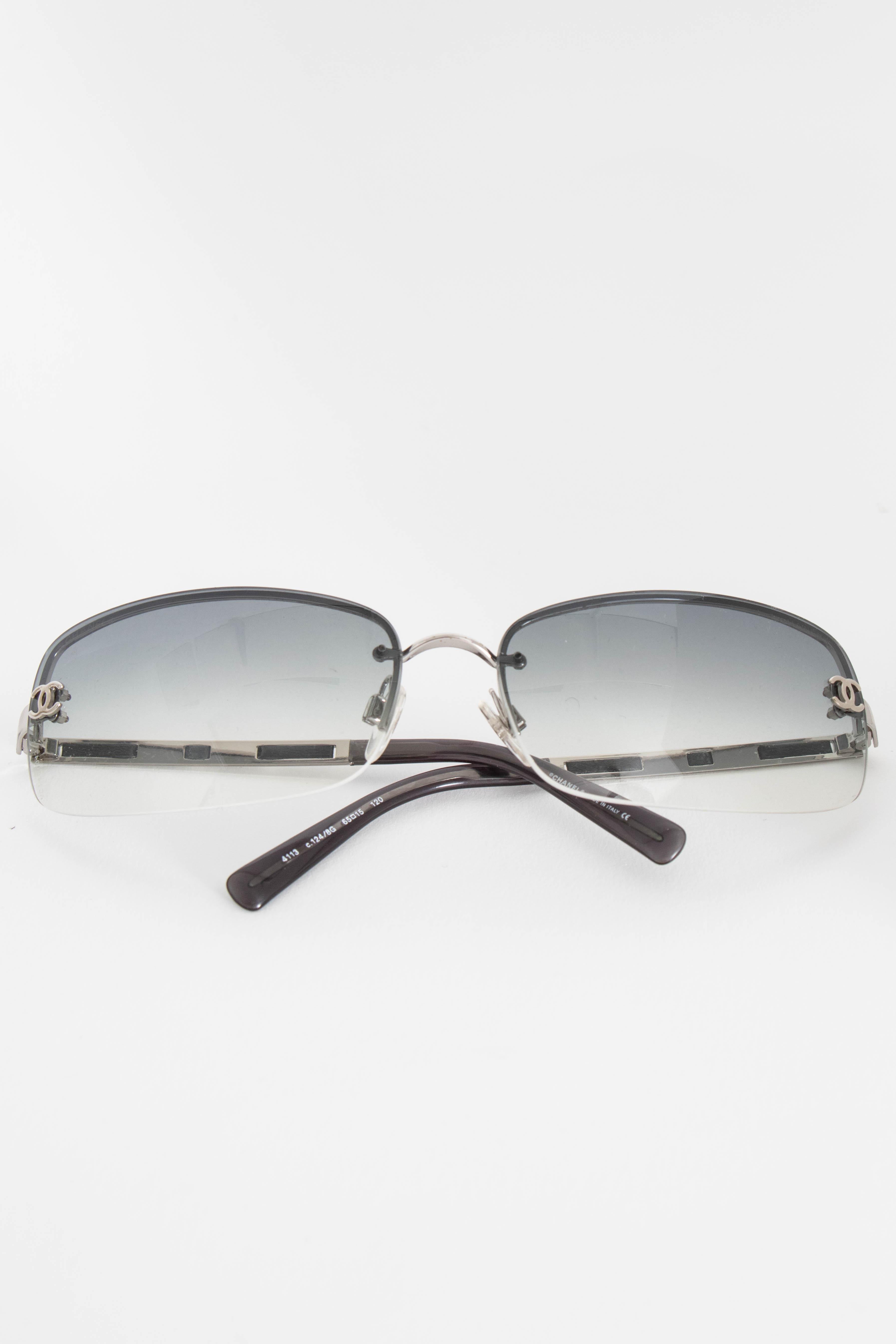 A pair of 1990s Chanel silver frame sunglasses with leather details along the temple and small Chanel double 'C' logos placed on both corners of the glasses. 

The sunglasses measure:
Temple length: 11.5 cm
Bridge: 1.5 cm
Eye width: 6.5 cm