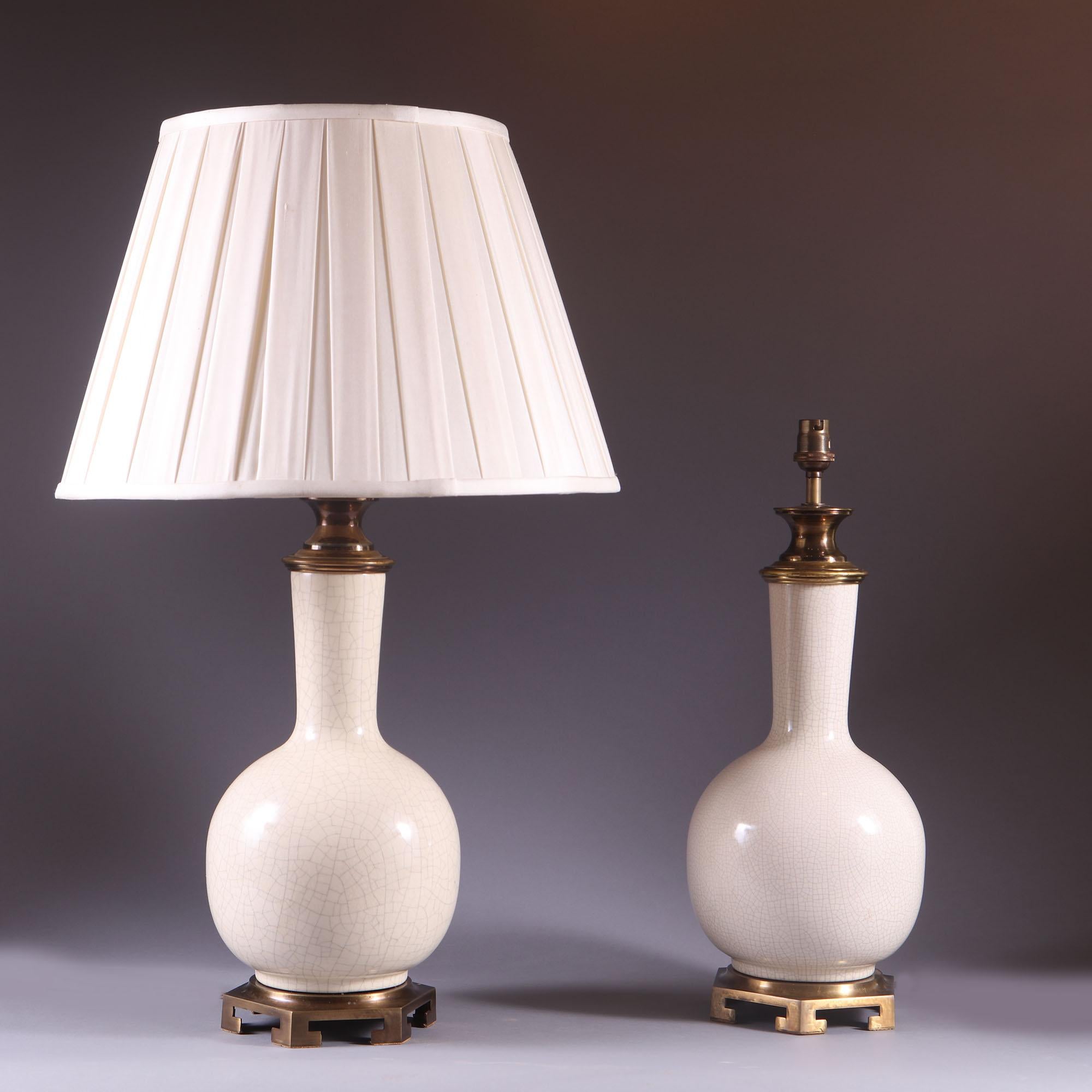 Pair of late 19th century Crackleware lamps on gilt bronze bases.
These beautiful vases hold a bulb shape with the crackle patterning around the whole base of the vase. They are an elegant off white tone offset by the gilt bronze to the base and