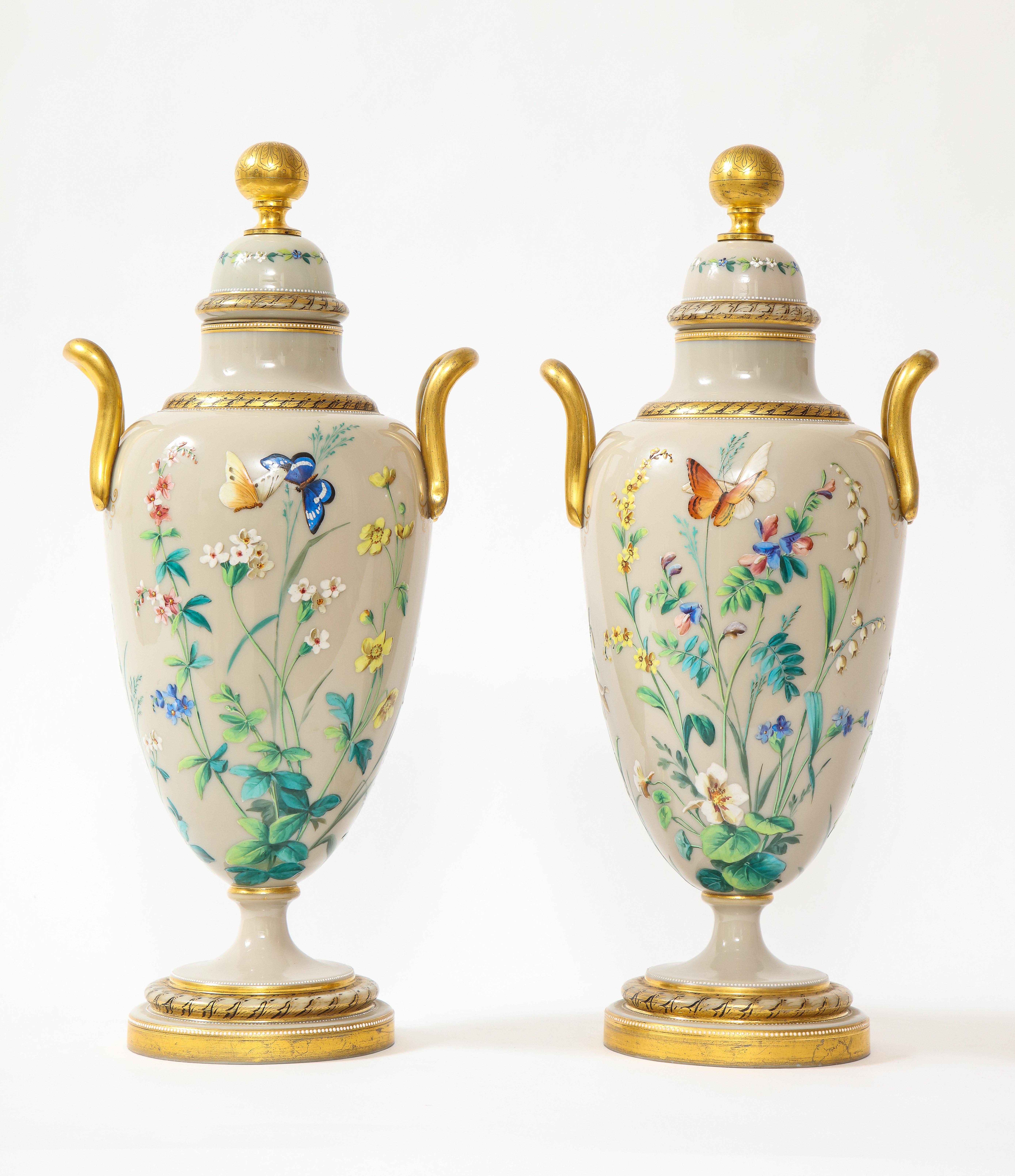 A fantastic and quite large pair of French Louis XVI style Baccarat grey opalescent ground hand-enameled vases with 24k gold decoration. Each is exquisitely hand-made with a fine opalescent grey ground crystal body and cover, each with finely