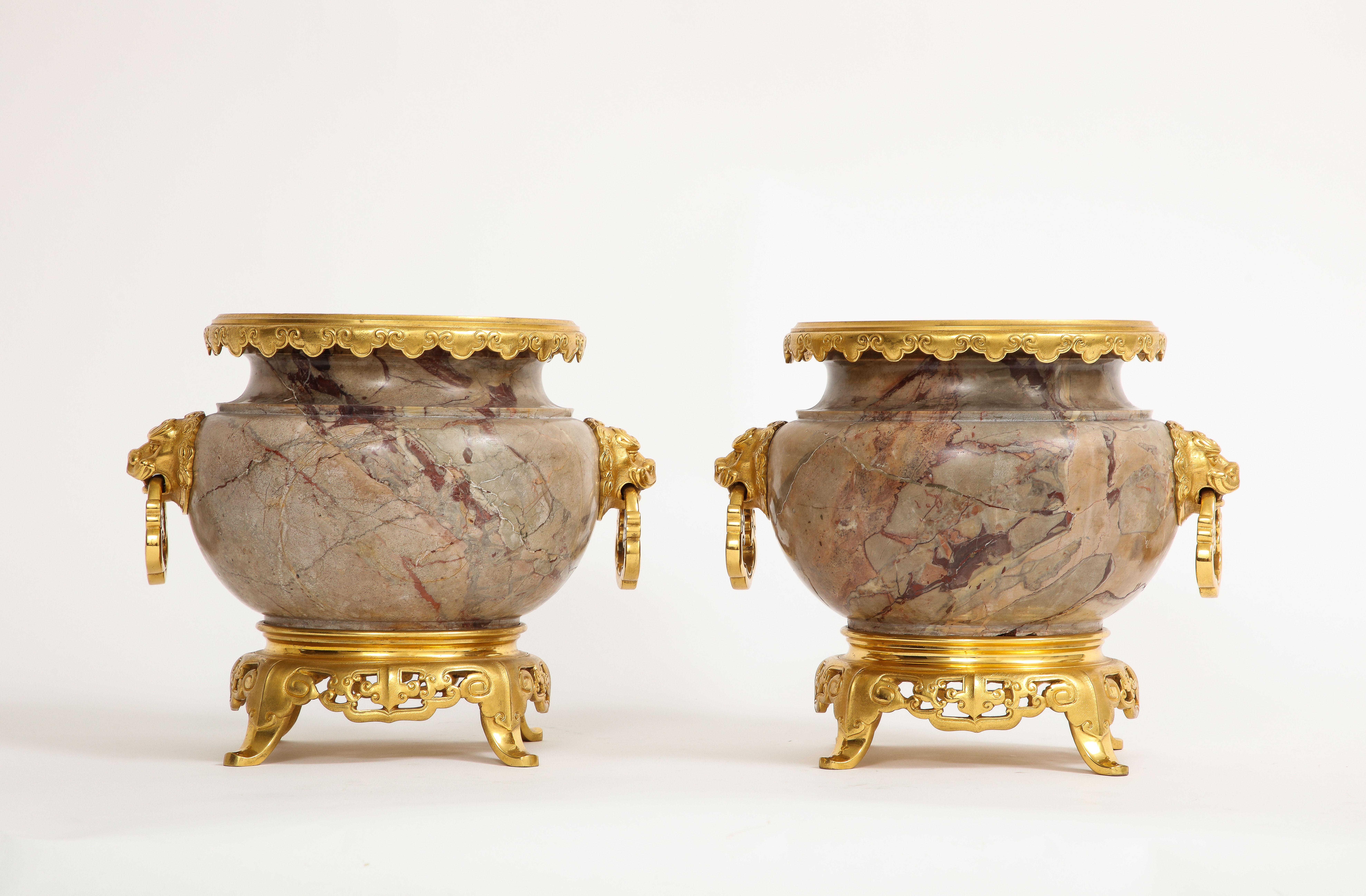 A Pair of 19th century French Ormolu Mounted Marble Centerpieces, Attributed to E. Lievre, Signed on the Bottom. Each bulbous-bodied centerpiece is set on Chinese-style ormolu bases, each composed of four stylized, scrolled legs. The vases have been