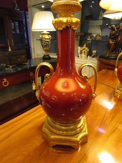A pair of 19th c French sang de boeuf porcelain and gilt lamps with crystal tops