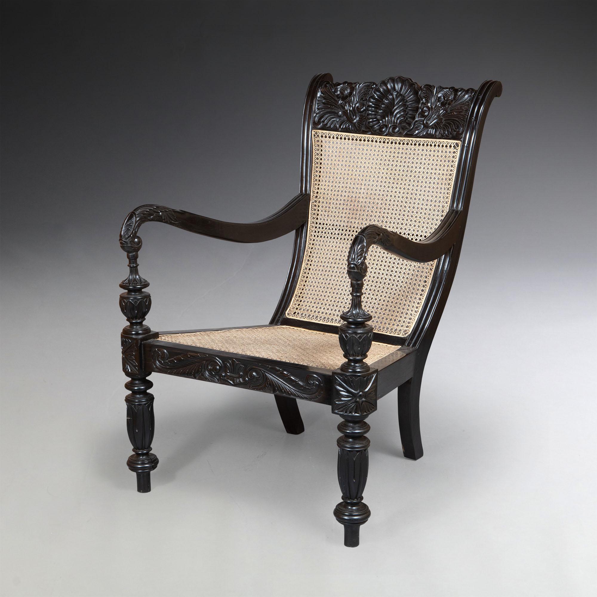 A fine pair of large scale Ceylonese ebony library armchairs chairs, with well carved backs and reeded scroll arms, resting on turned fluted legs, with cane seats.

Ceylon, circa 1840.