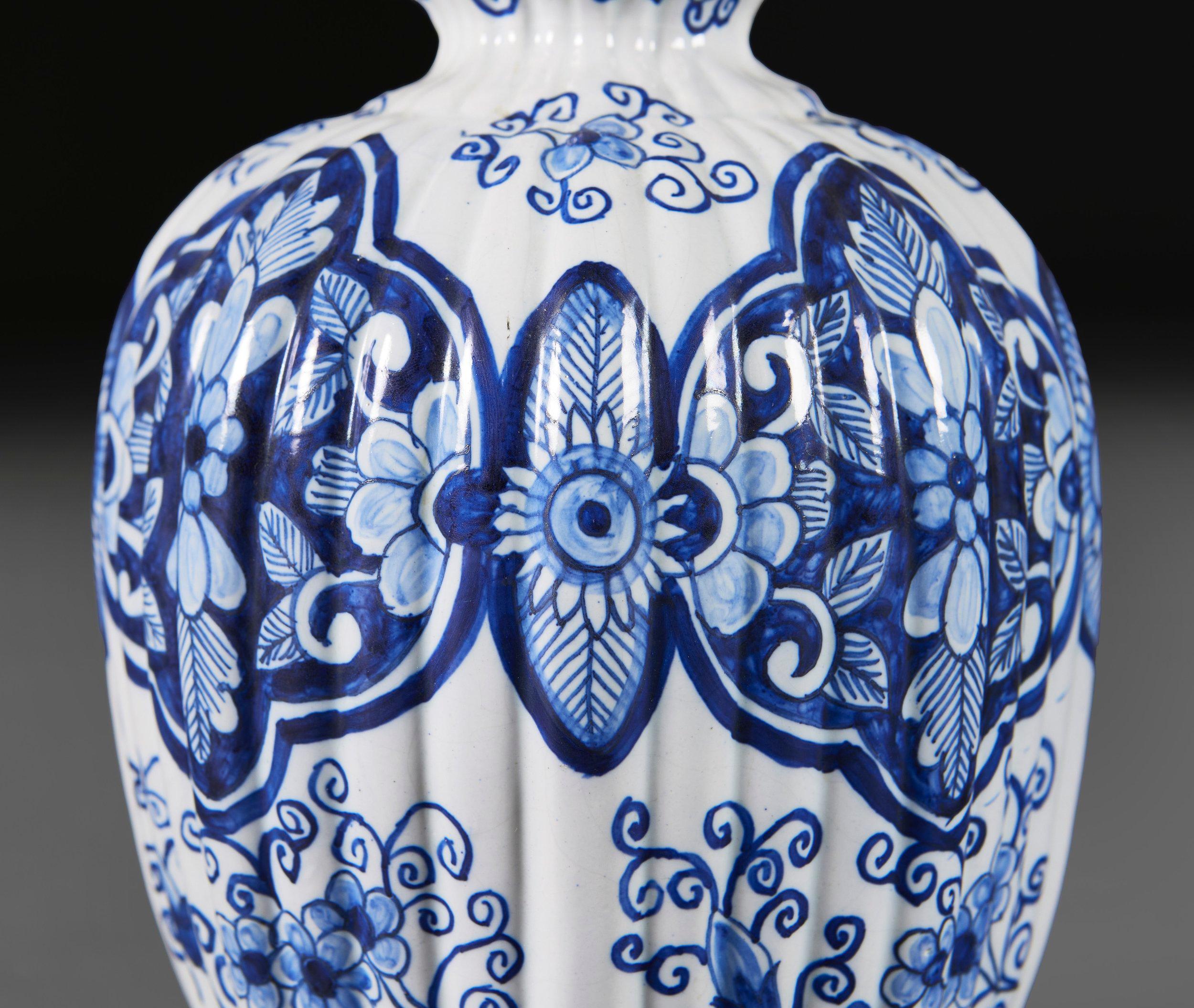 A pair of mid nineteenth century Delft lamps of gadrooned double gourd form, with blue foliate decoration throughout, on a white ground, mounted on turned giltwood bases.

Please note:

Lampshades not included. Lamps have been photographed with a