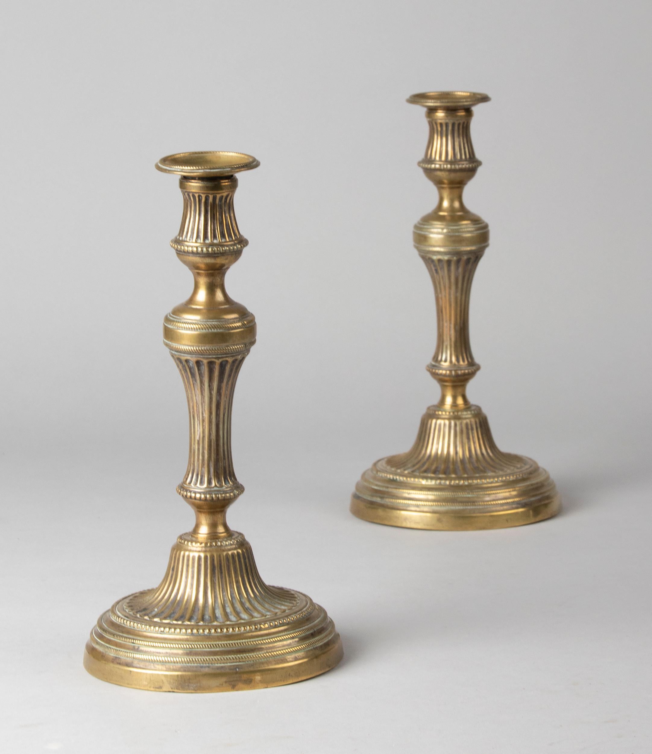 A beautiful pair of 19th century antique brass candlesticks. The candlesticks are decorated with canalures and ornate edges in Louis 16 style. They come from France and are in good condition. They are sturdy and stable.