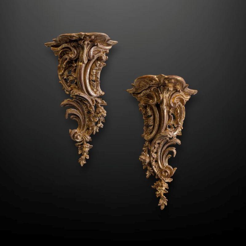 A Pair of 19th Century Carved Giltwood Rococo Wall Brackets.
Both are decorated with an asymmetric pierced foliate design featuring richly carved rococo C scrolls interspersed with flowers and leaf work.

The rocaille brackets depict the typical